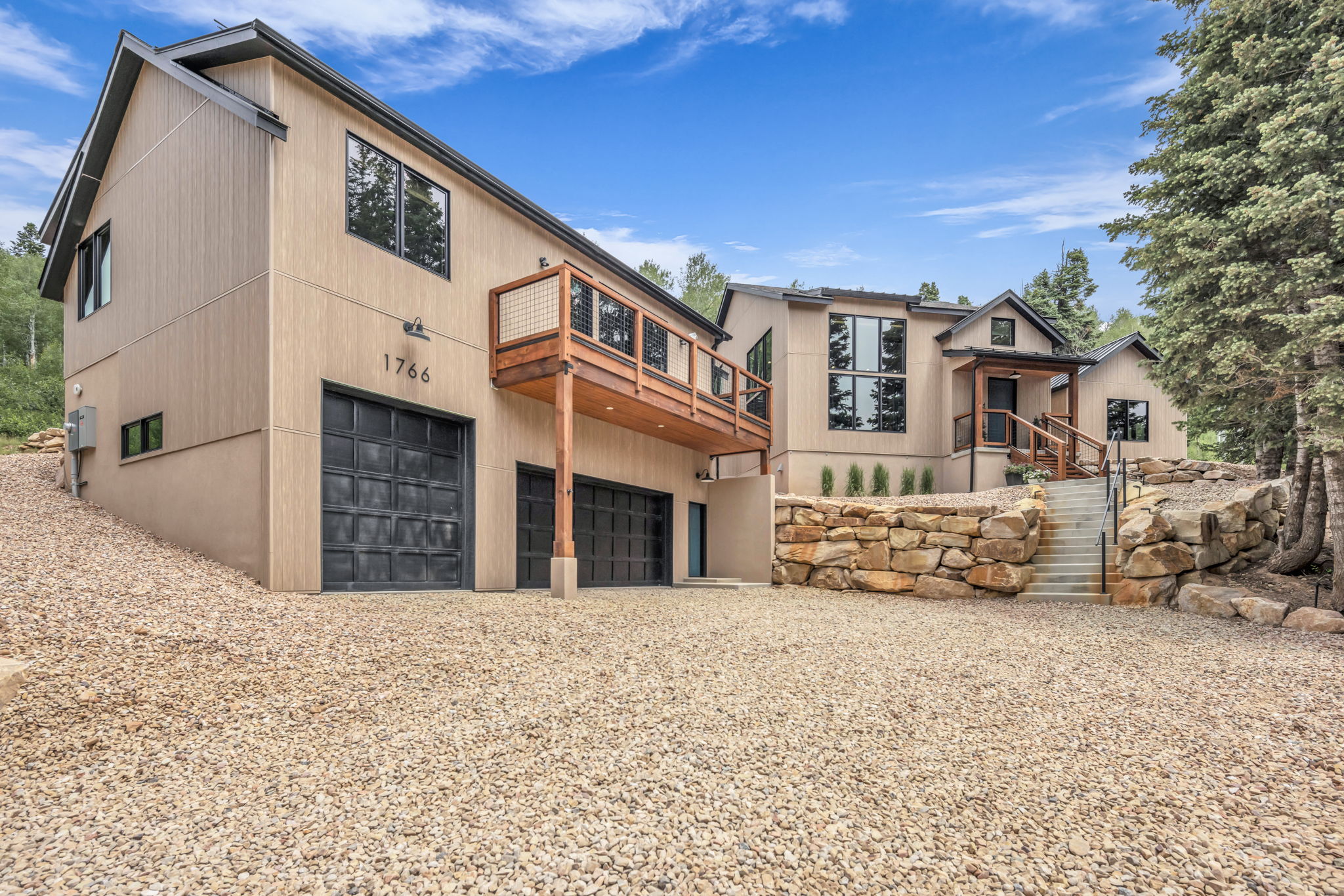 Contemporary exterior with multiple garage bays, a raised wood deck, and a gravel driveway