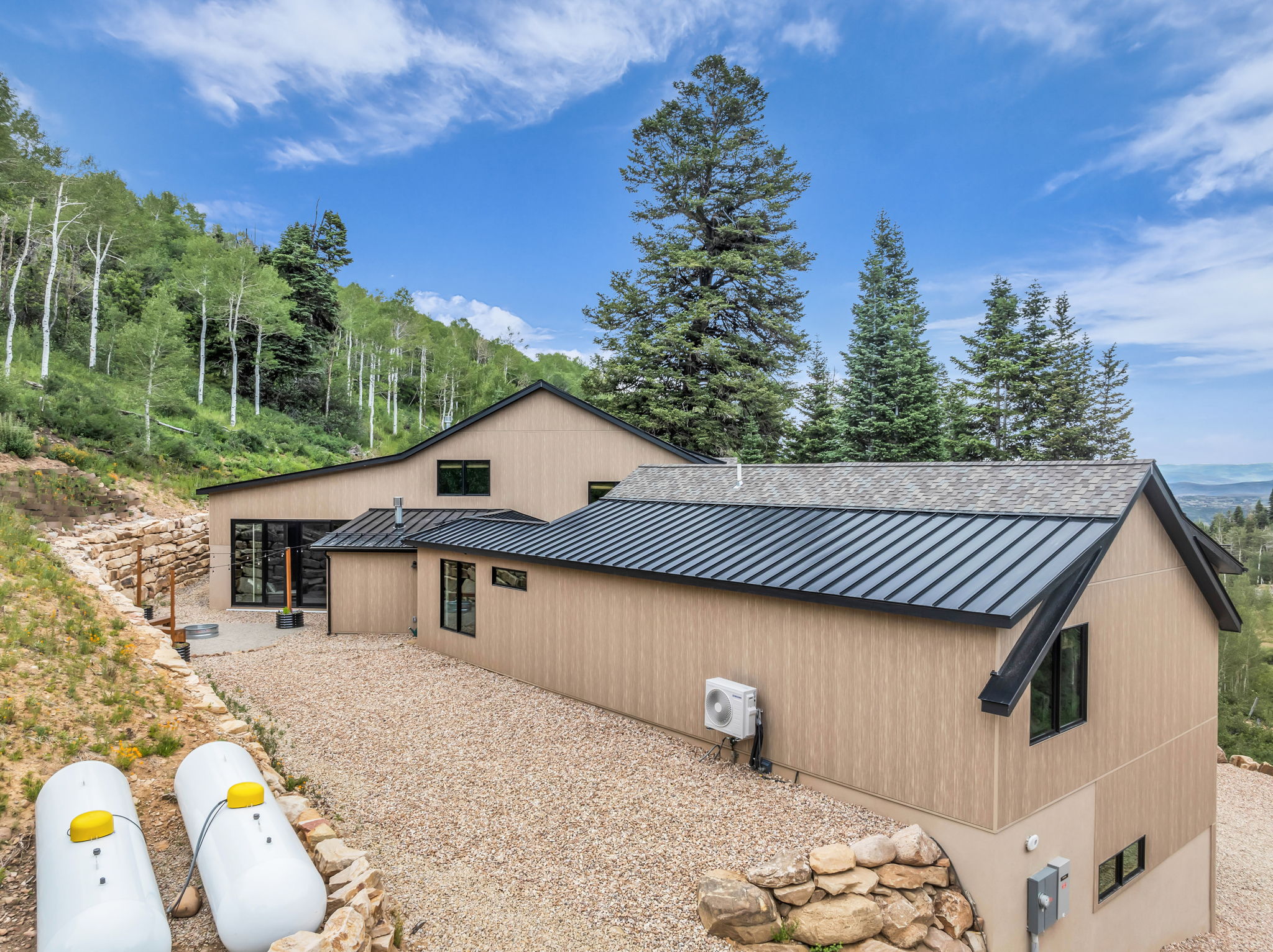 Exterior featuring light-toned vertical siding and a combination of shingle and standing seam metal roofing