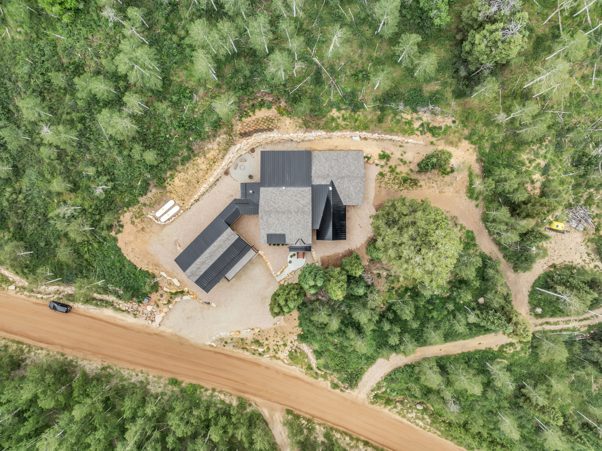Aerial perspective showcasing a modern residence with a multi-pitched roofline and an attached covered structure