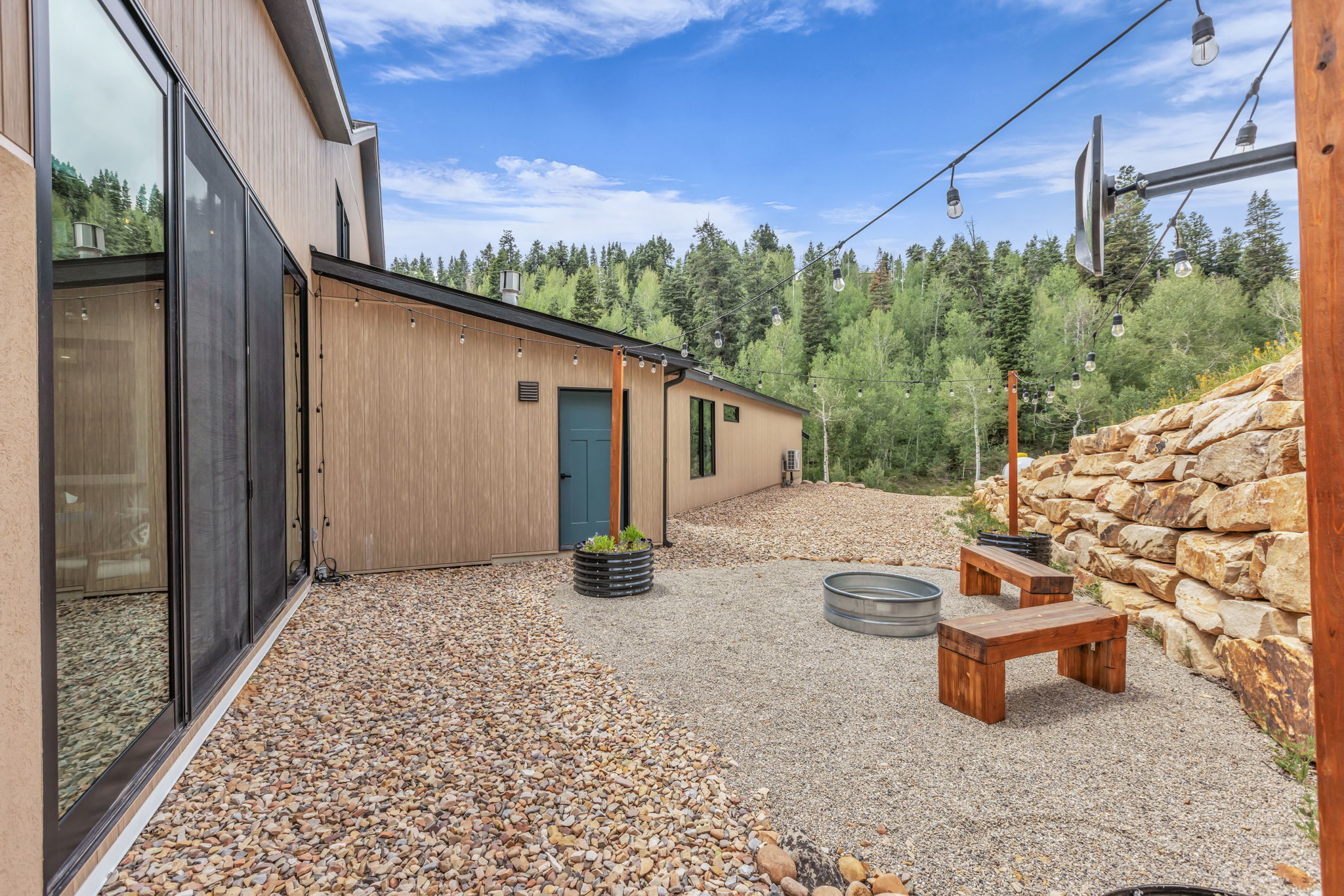 Gravel patio featuring a stone retaining wall and string lighting