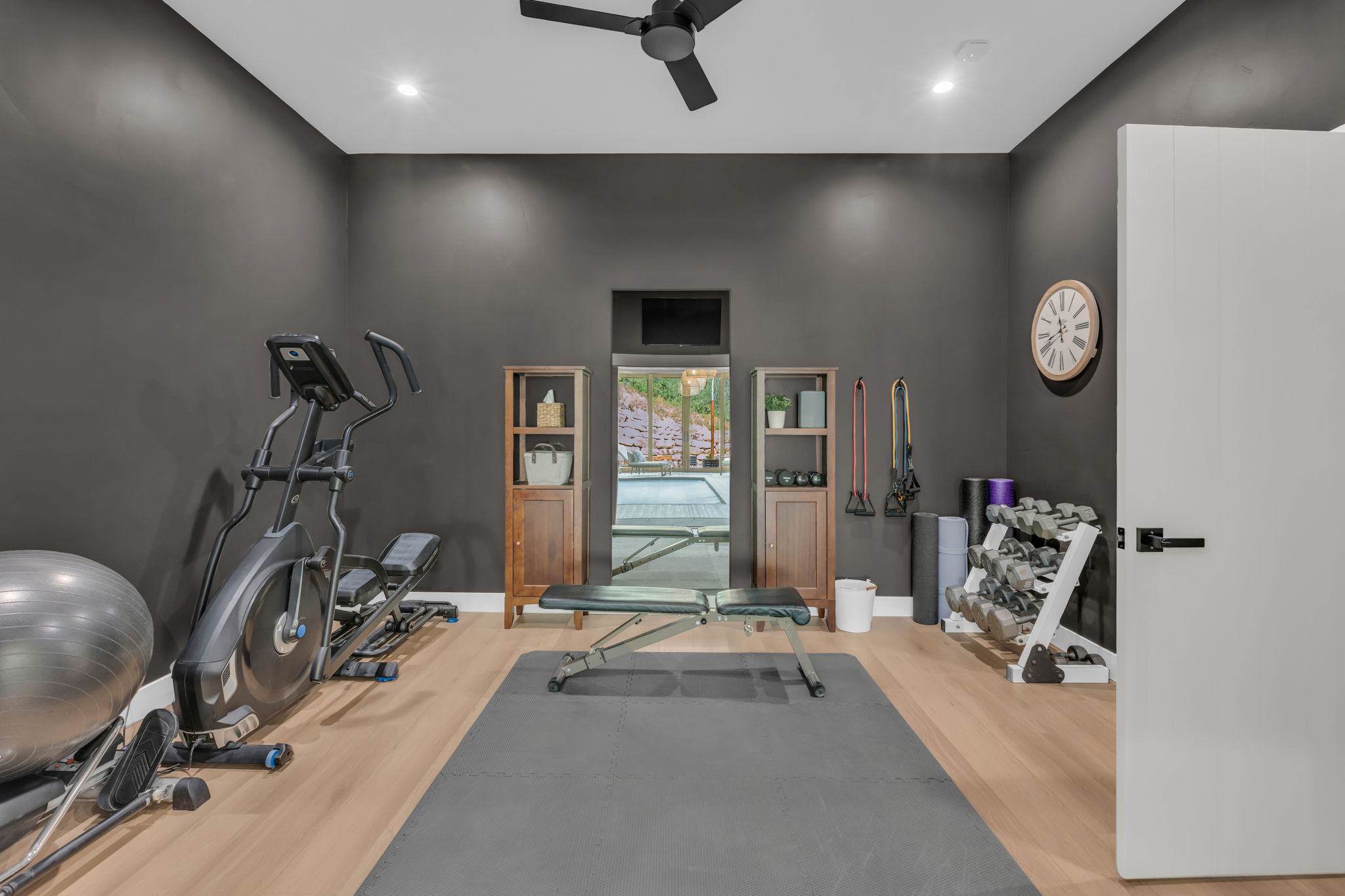 Dedicated fitness space featuring light wood-finish flooring and dark gray walls