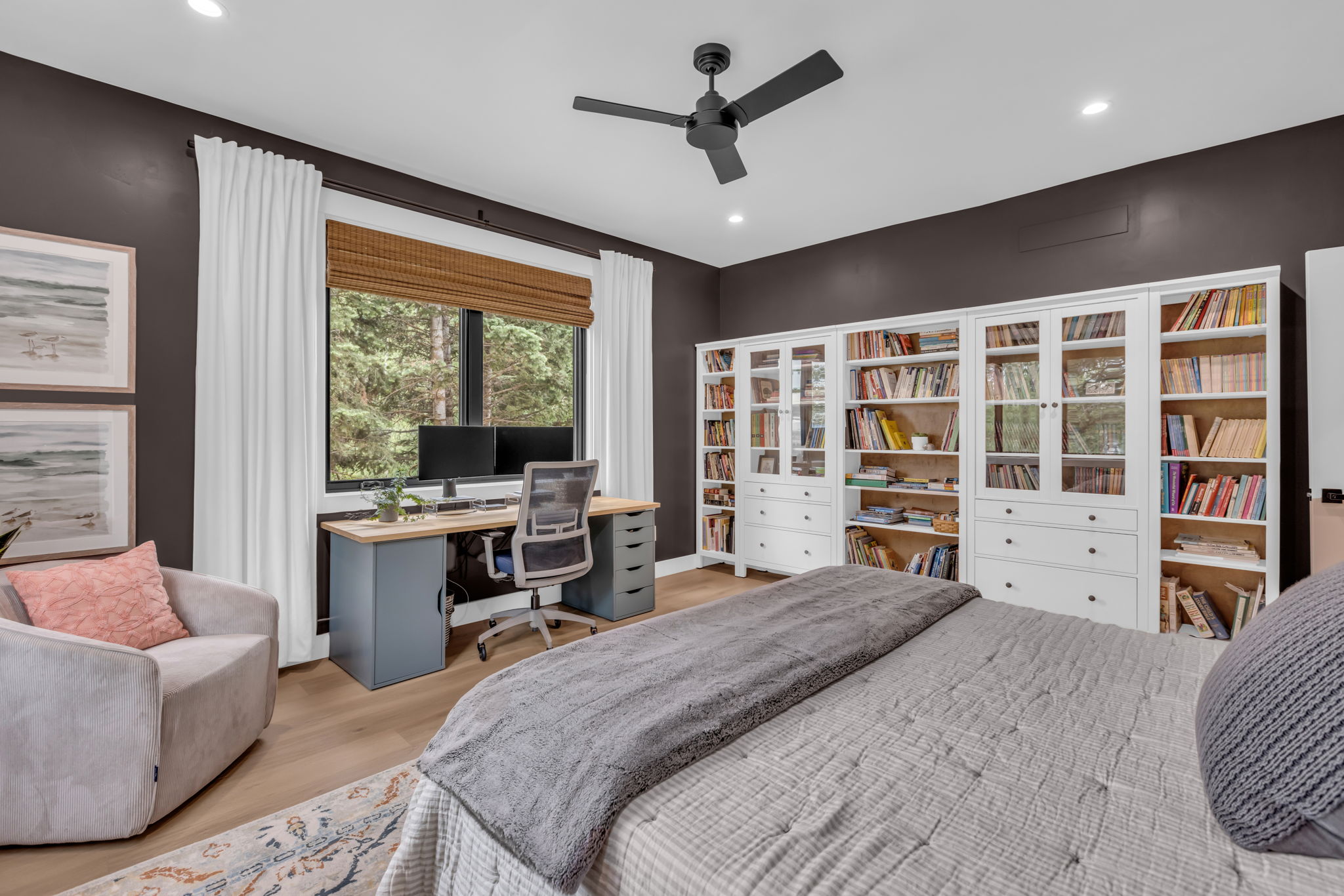 Spacious room featuring extensive built-in white cabinetry with glass-front doors, a dedicated workstation with a wood-finish desktop, and recessed lighting