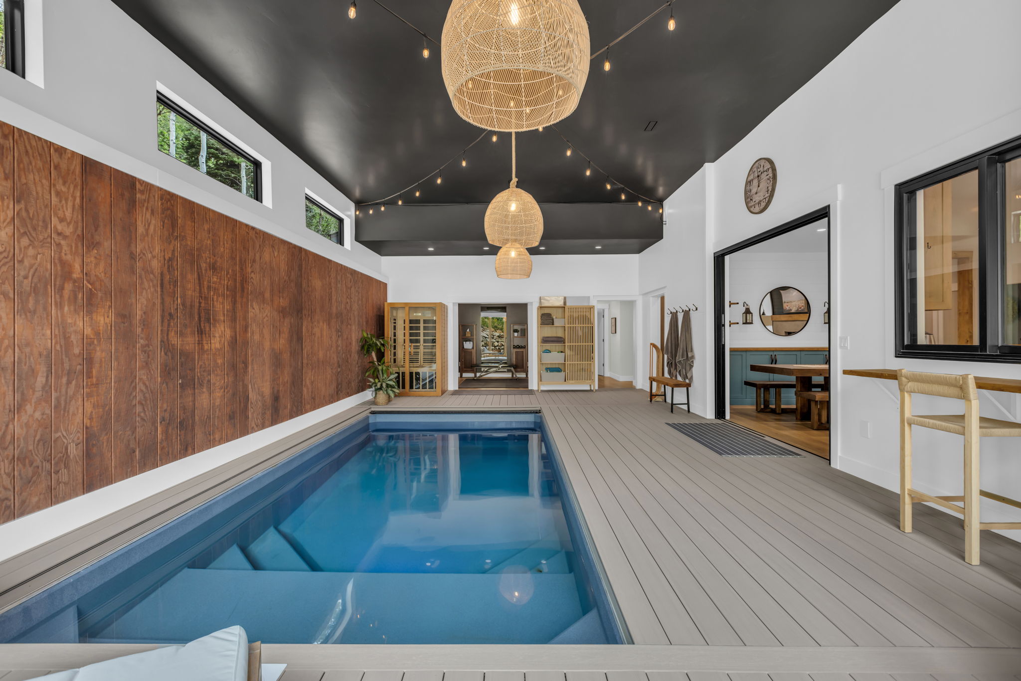 Indoor swimming pool featuring steps, composite decking, and a wood-finish accent wall