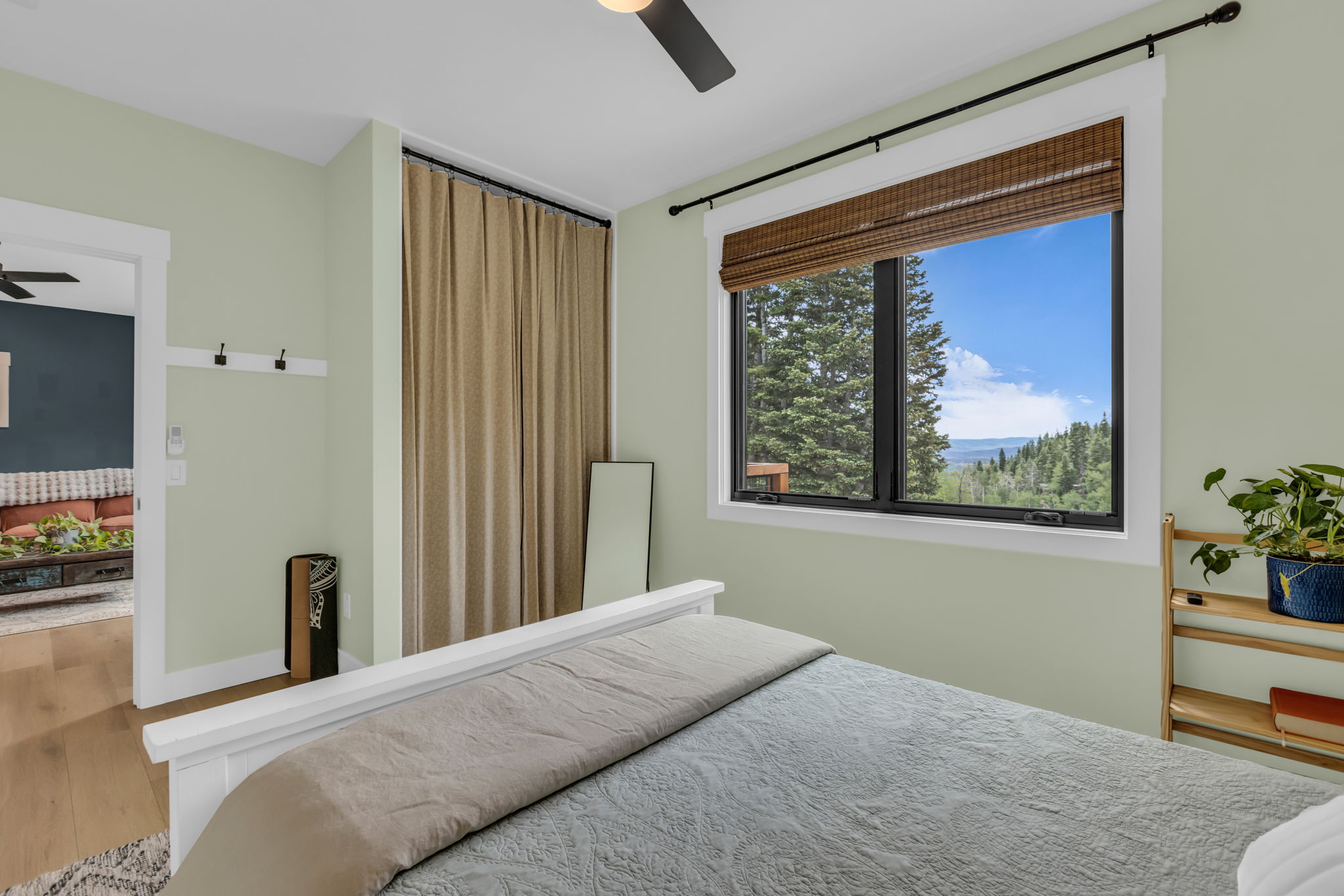 Bedroom featuring a large window with mountain scenery, a ceiling fan, and wood-finish flooring