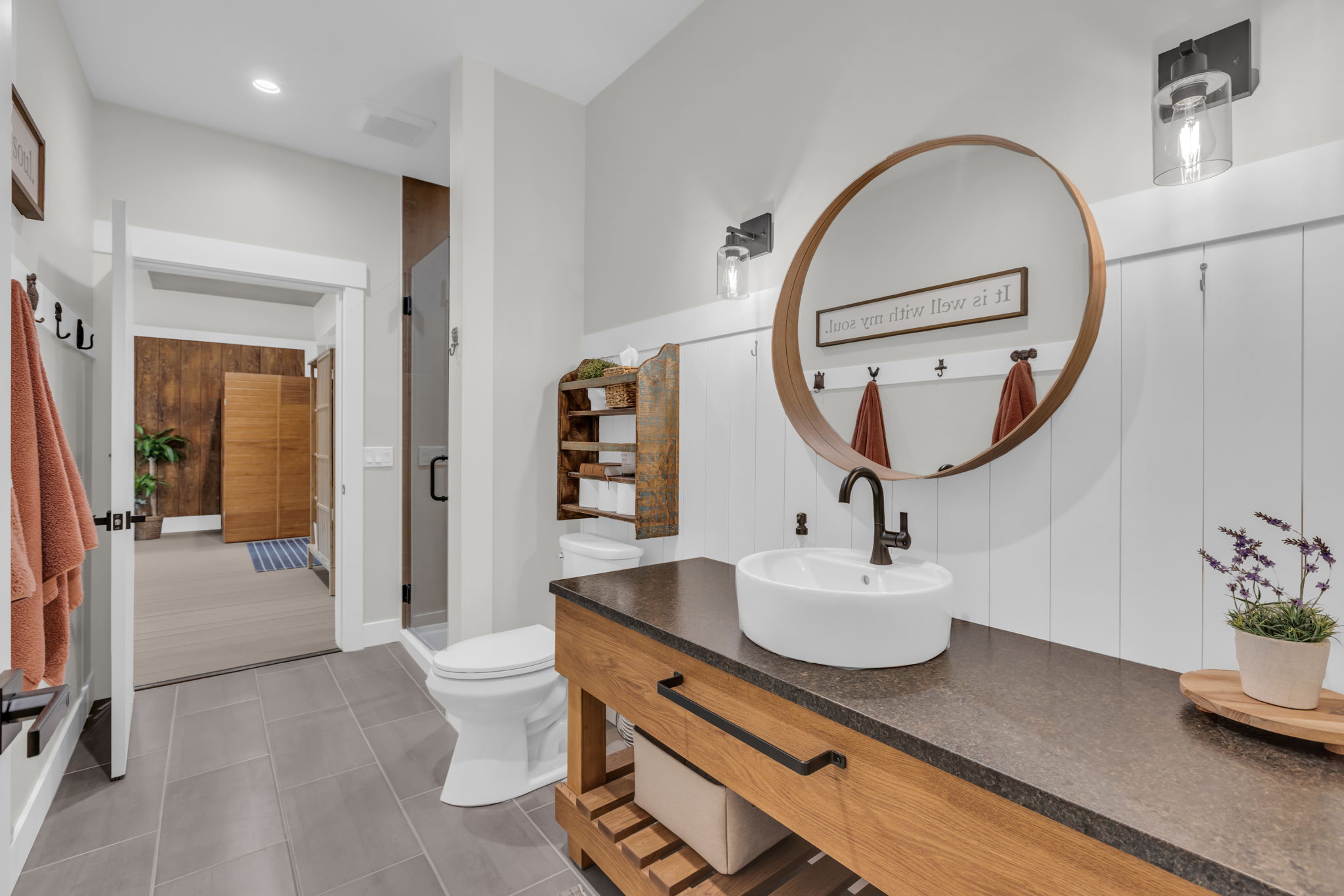 Modern vanity featuring a vessel sink, dark countertop, and wood-finish cabinetry