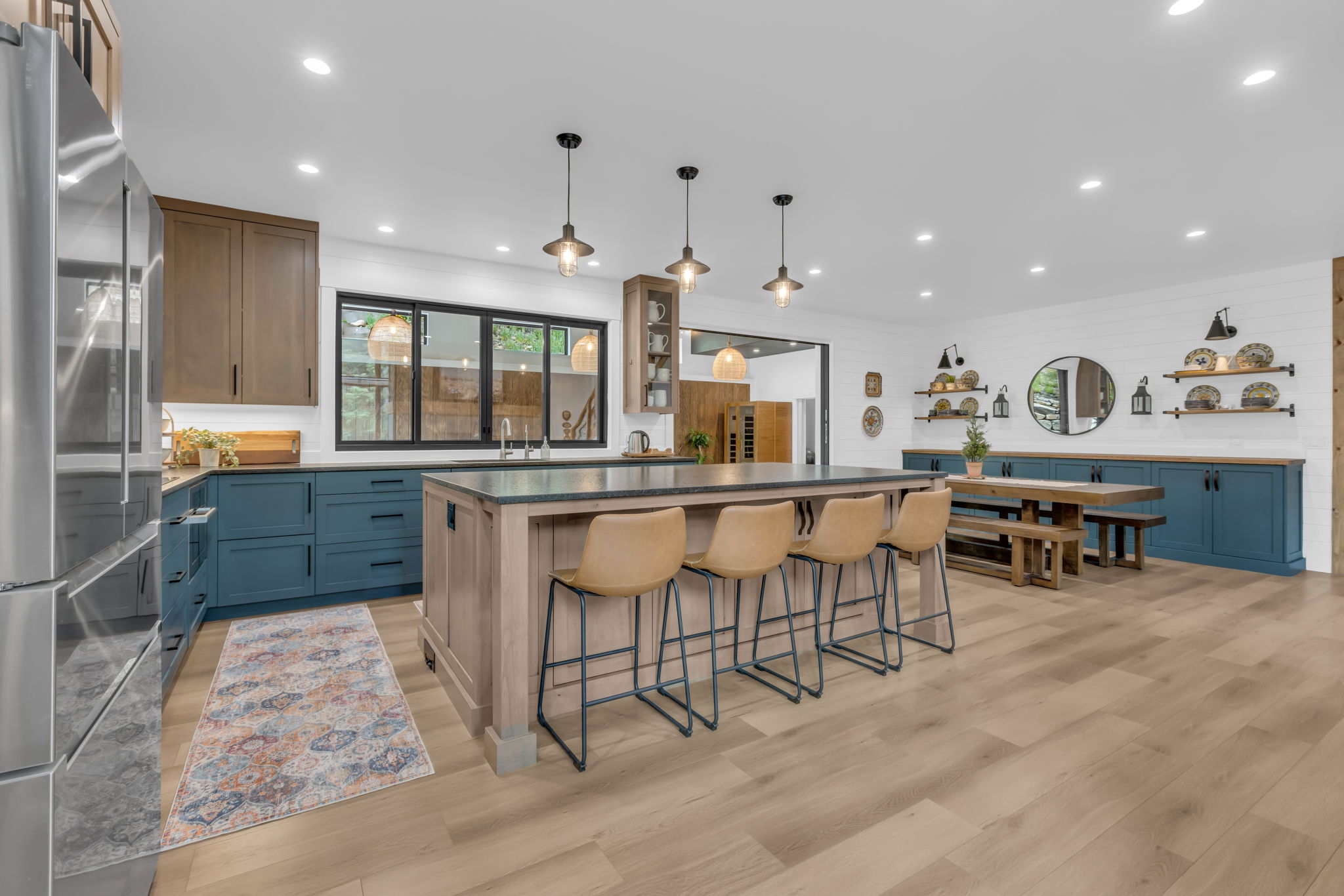 Open-concept kitchen featuring an oversized island with seating, a stainless steel refrigerator, and wood-finish flooring