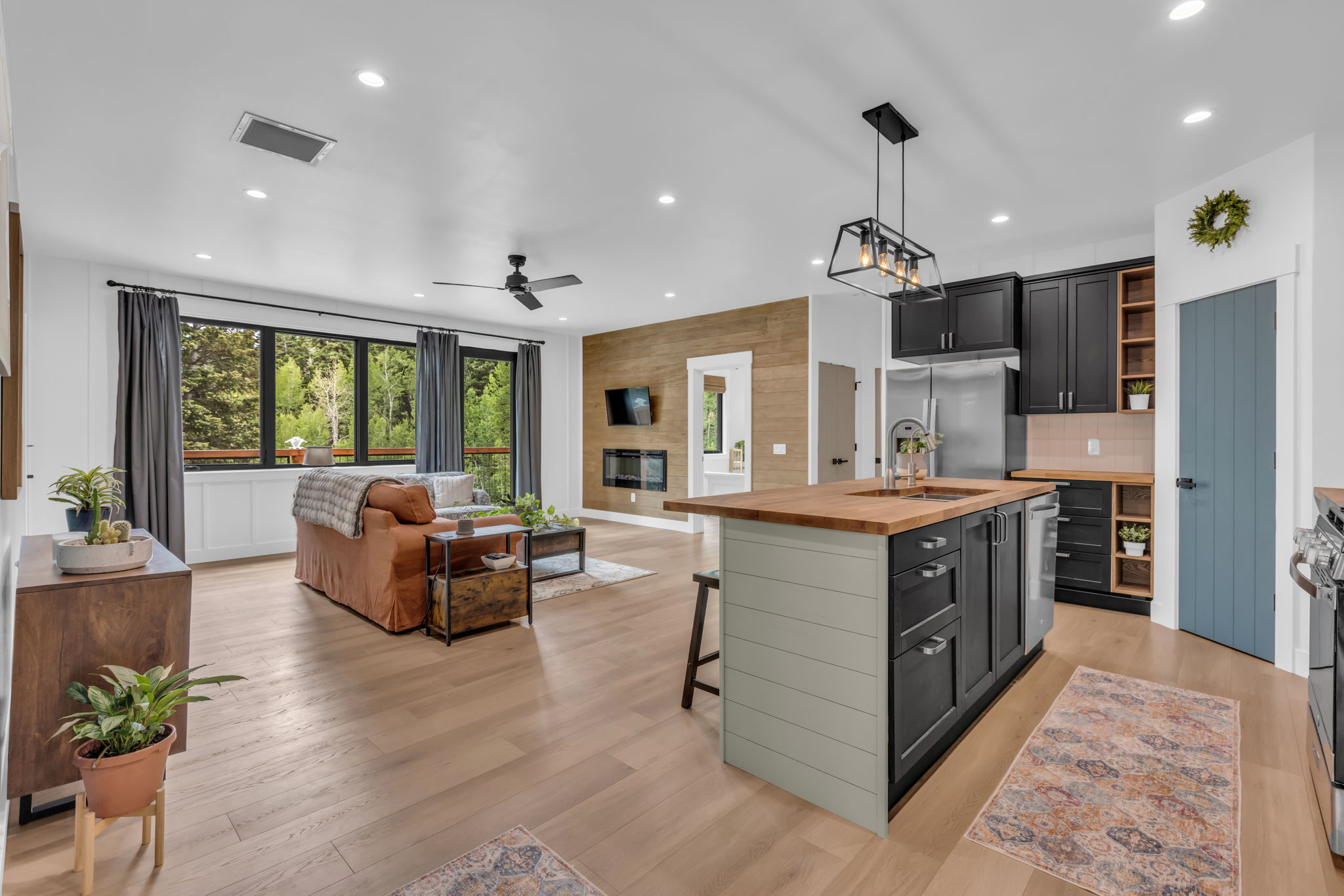 Open-concept living space featuring wood-finish flooring, recessed lighting, and a linear electric fireplace