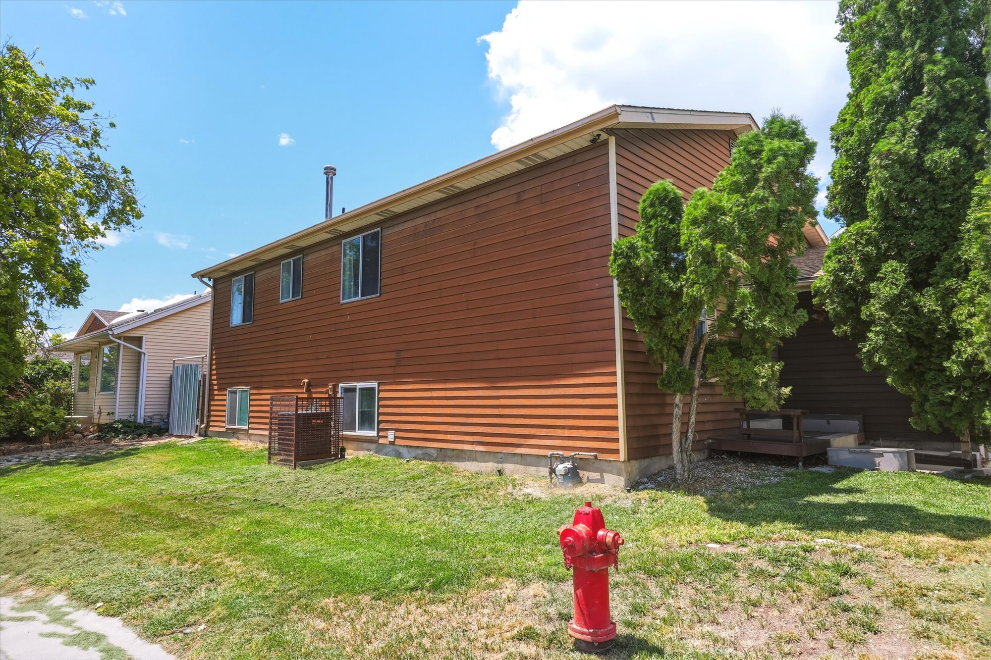 Brown horizontal siding exterior featuring multiple windows, a foundation perimeter, and a partial outdoor deck