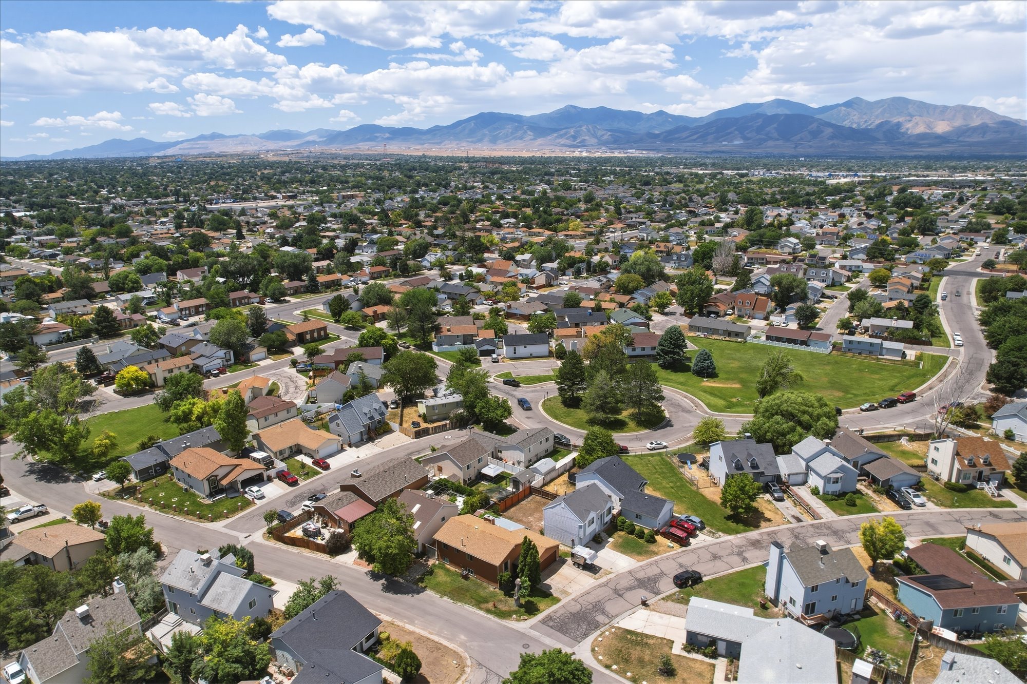 Expansive residential area featuring a variety of architectural styles, mature trees, and a mountain range backdrop