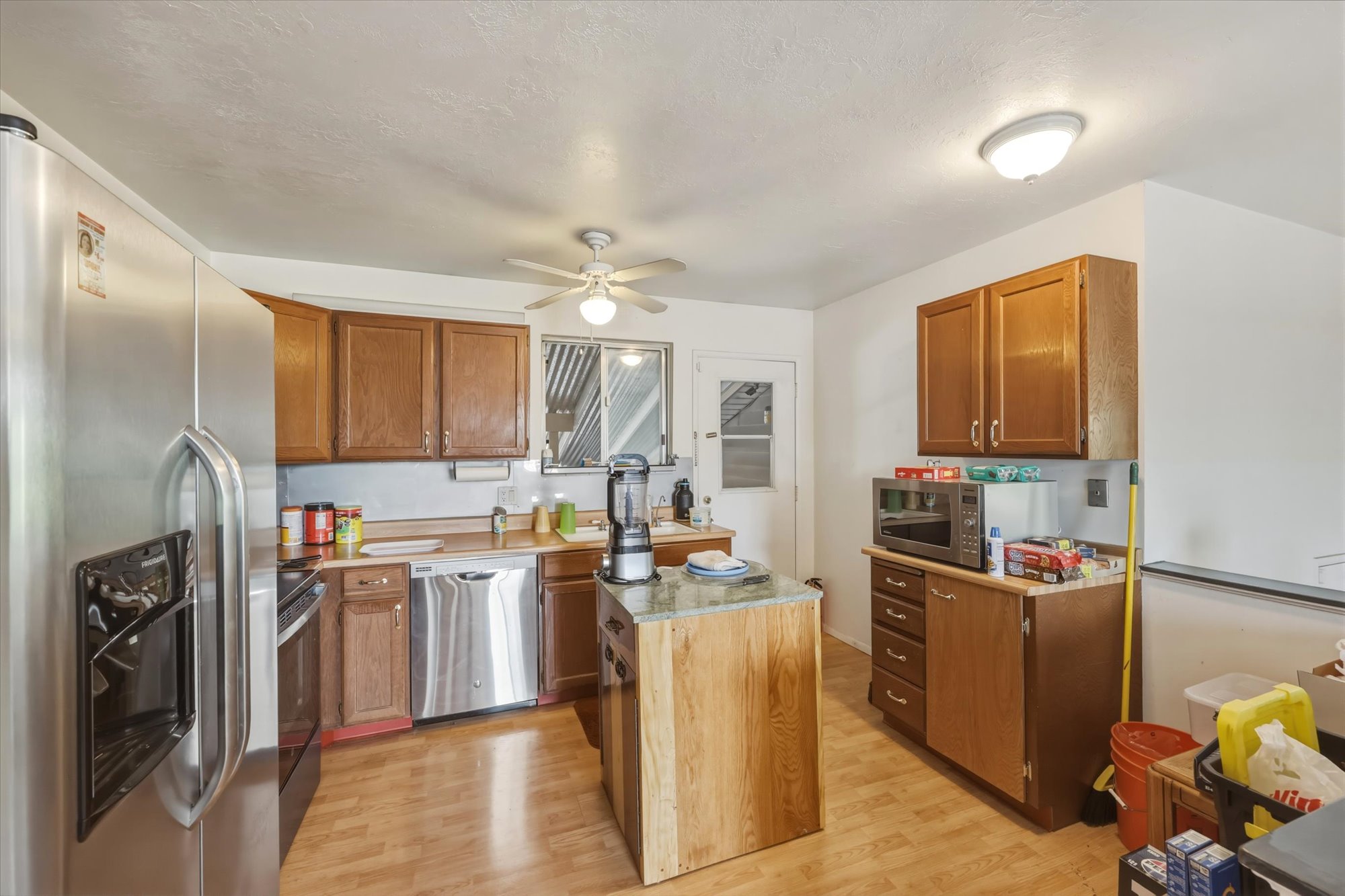 Kitchen with wood-finish flooring, wood cabinetry, and stainless steel appliances including a refrigerator, dishwasher, and range