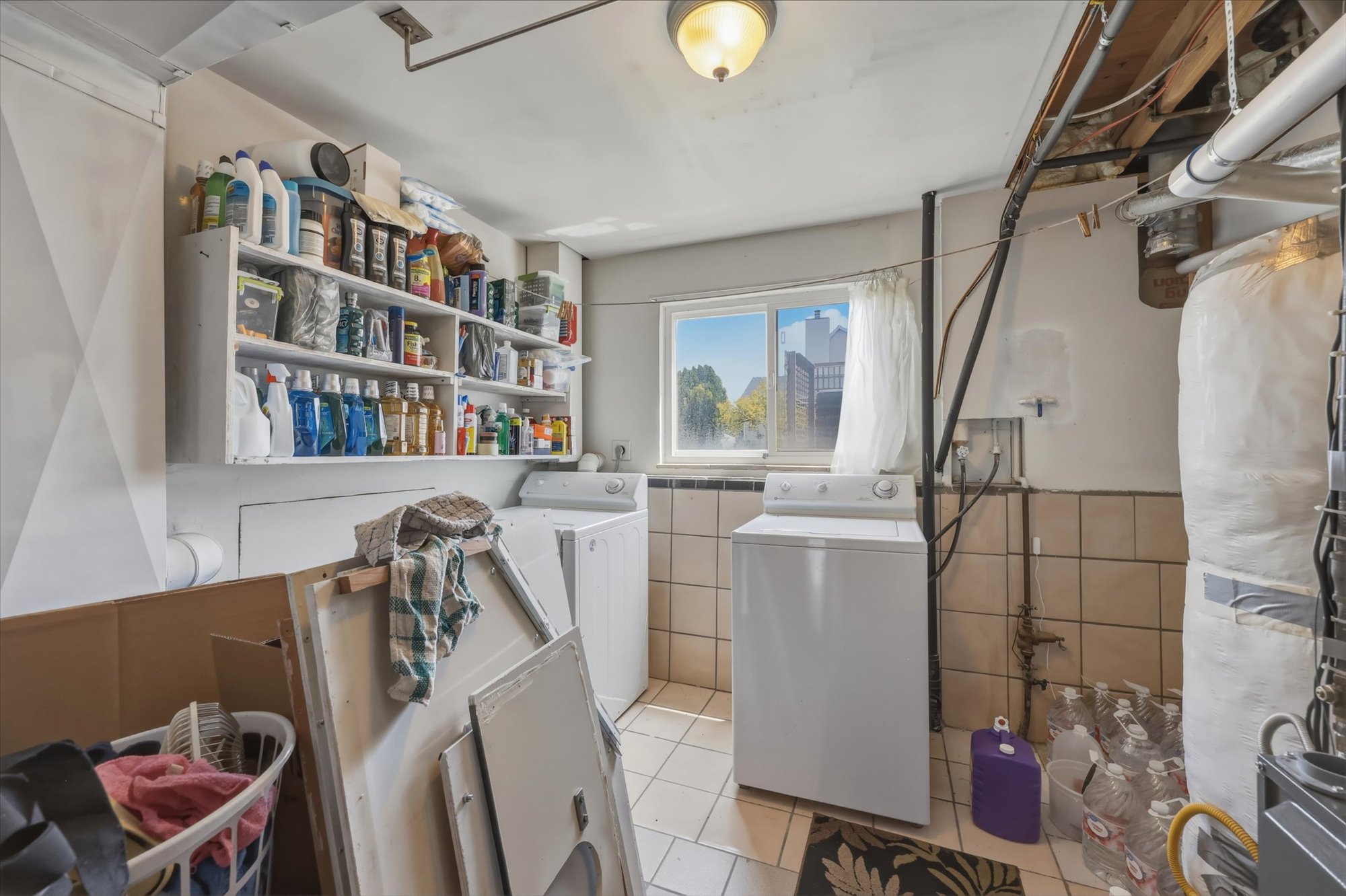 Utility room featuring a window, built-in shelving, and tiled walls