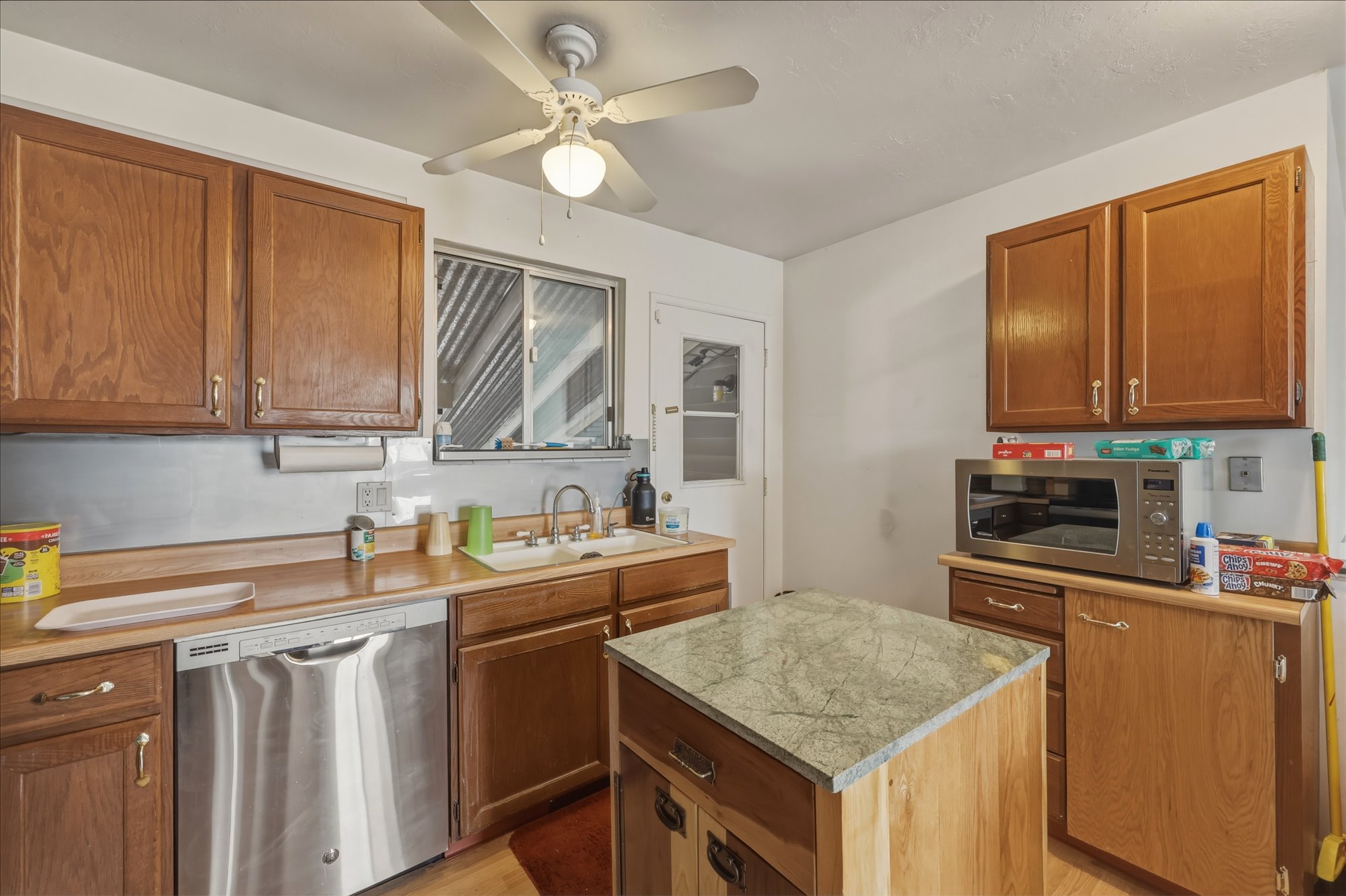 Kitchen featuring wood cabinetry, stainless steel dishwasher, wood-finish countertops, and a central island with a stone-finish countertop