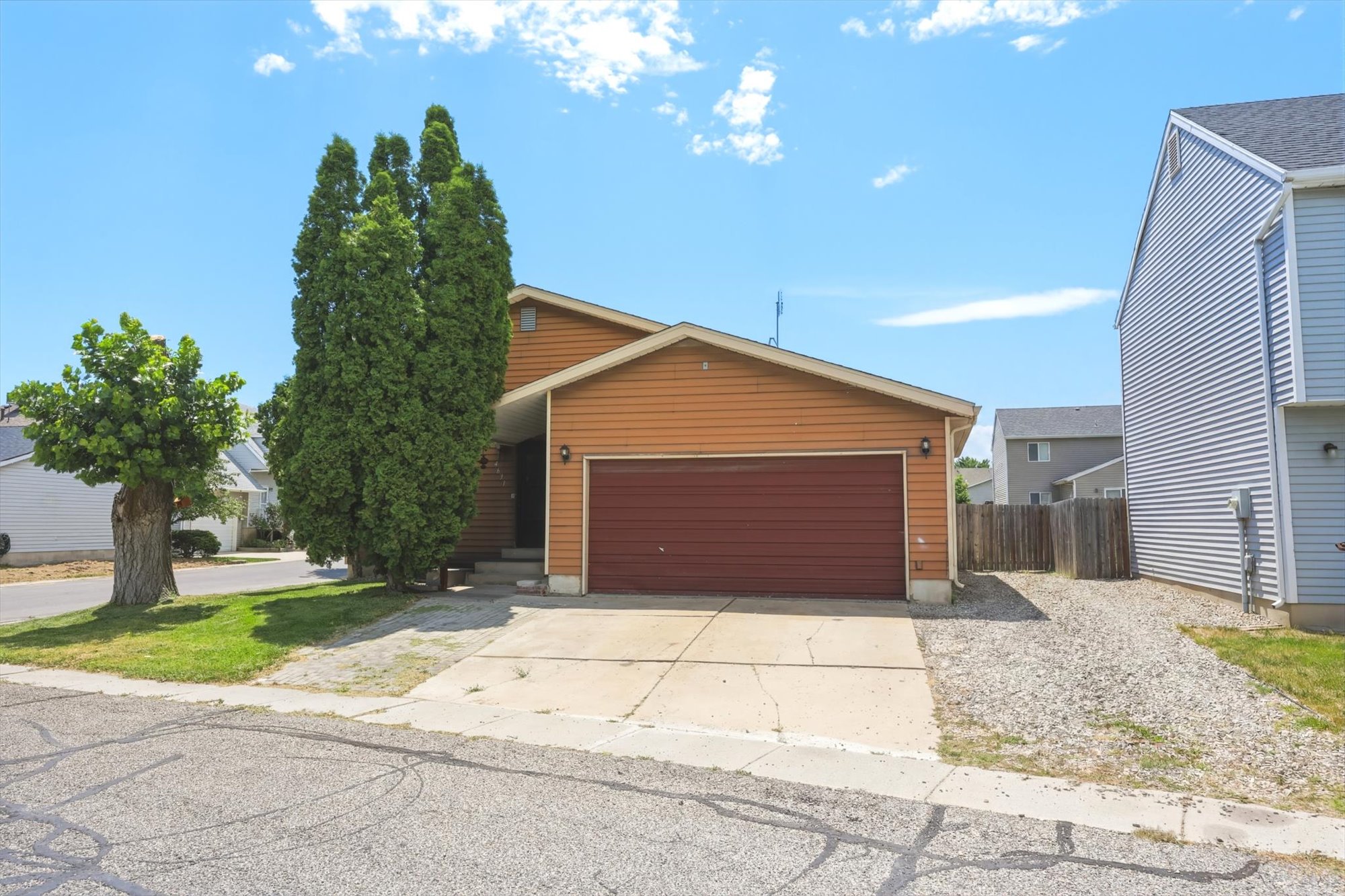 Single-family residence featuring tan horizontal siding, an attached garage with a brown door, and a concrete driveway