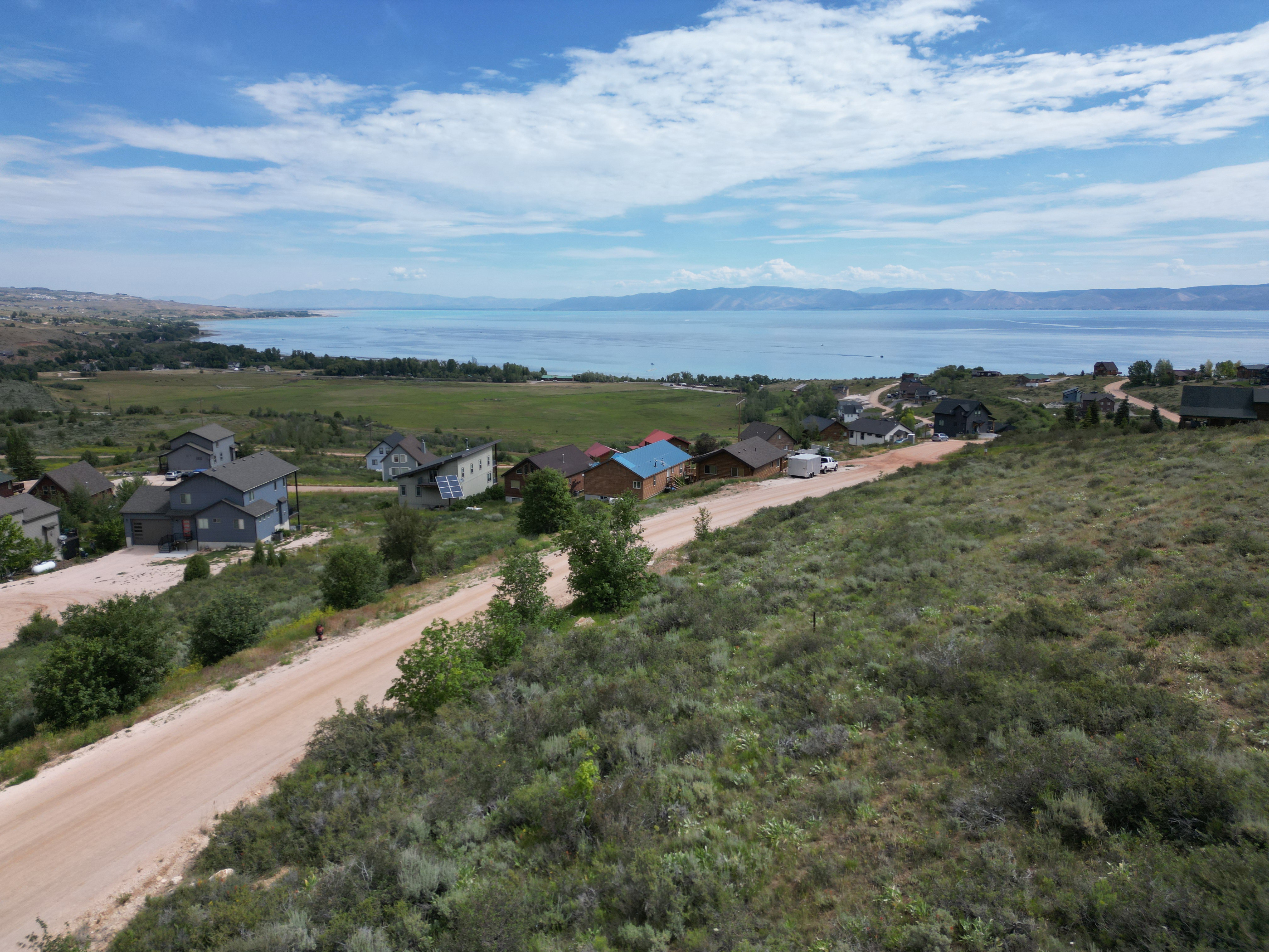 Expansive hillside lot featuring a dirt road, natural landscaping, and distant water views