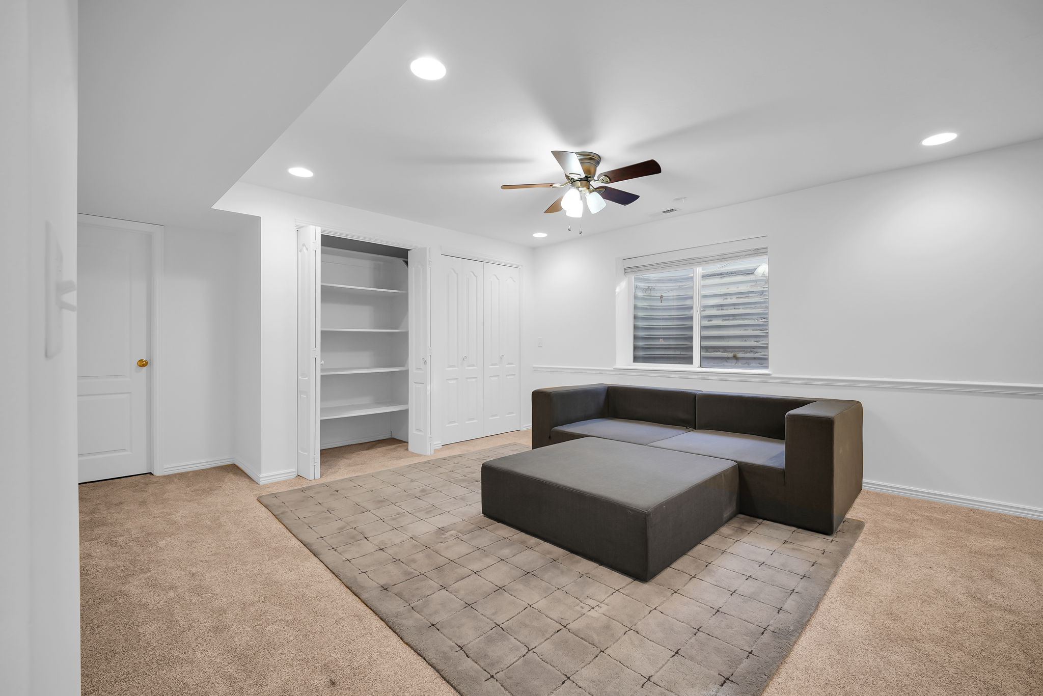 Spacious carpeted room featuring a ceiling fan, recessed lighting, and a window with blinds