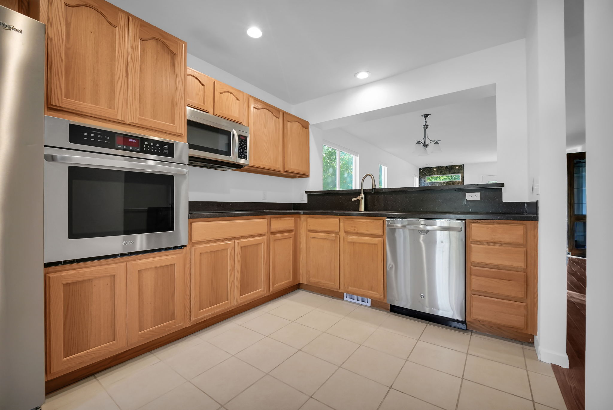 L-shaped kitchen featuring wood cabinetry, dark countertops, and tile flooring