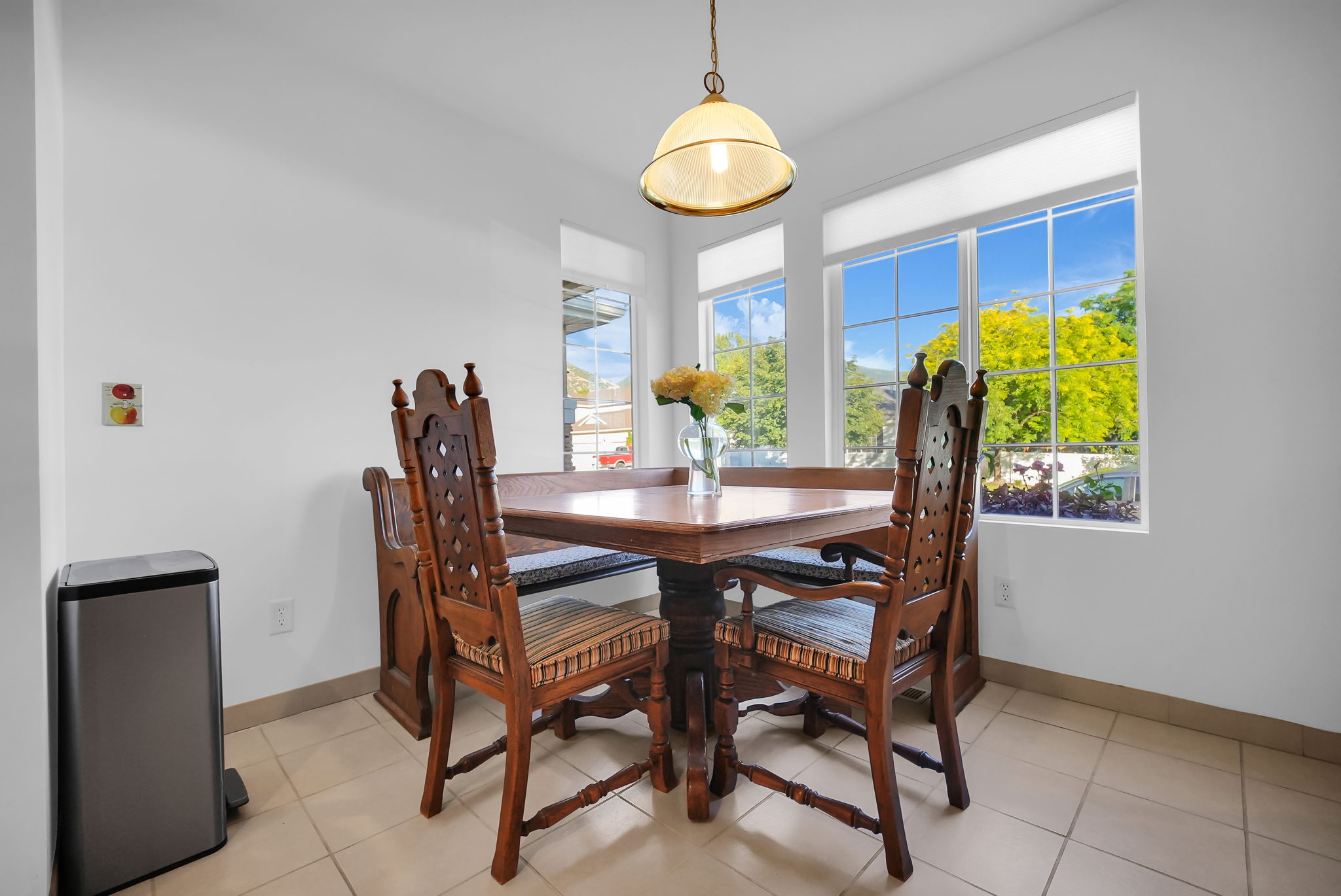 Dining area featuring a central chandelier, multiple large windows with grid patterns, and tile flooring