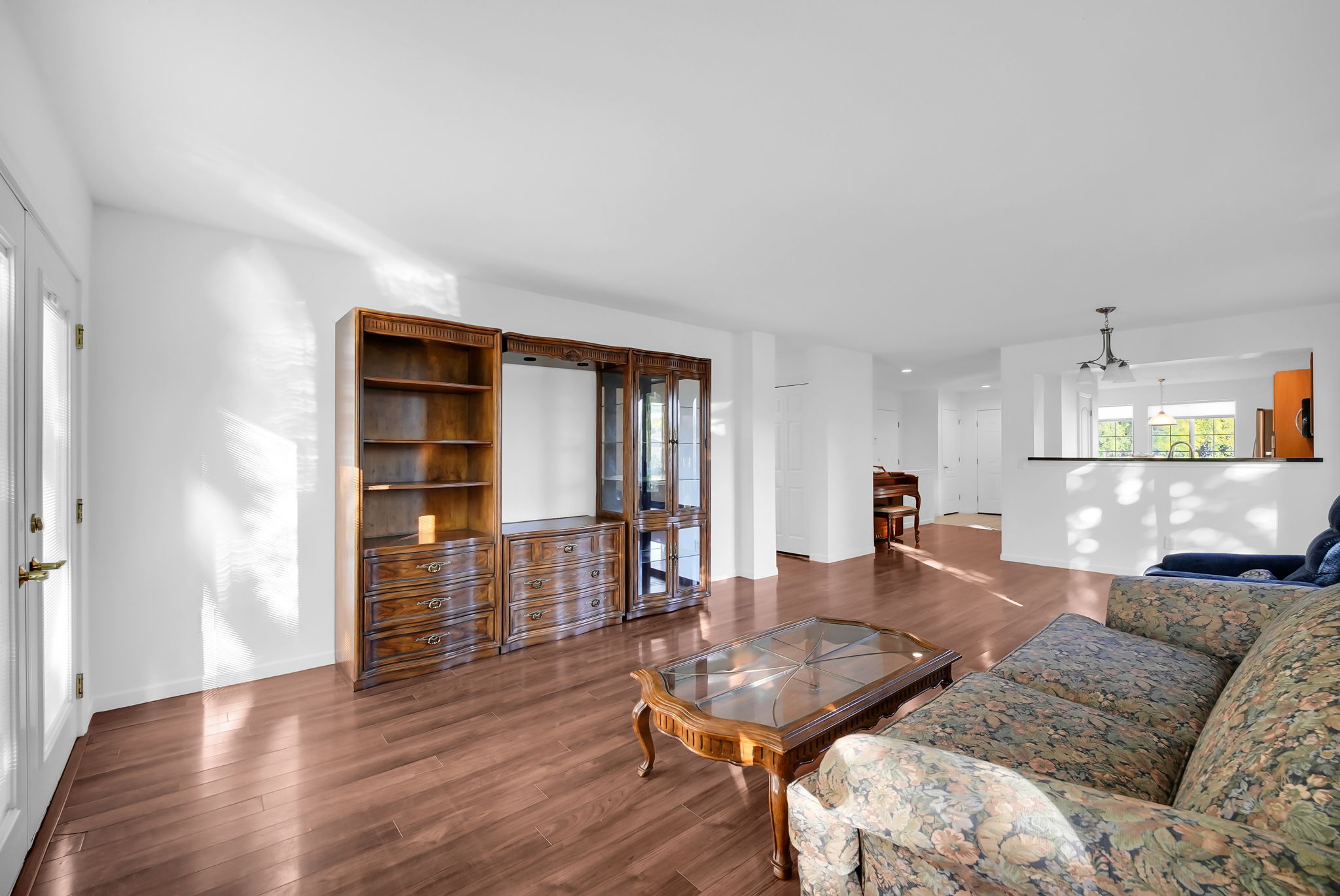 Spacious living area featuring wood-finish flooring, white walls, and a built-in entertainment center