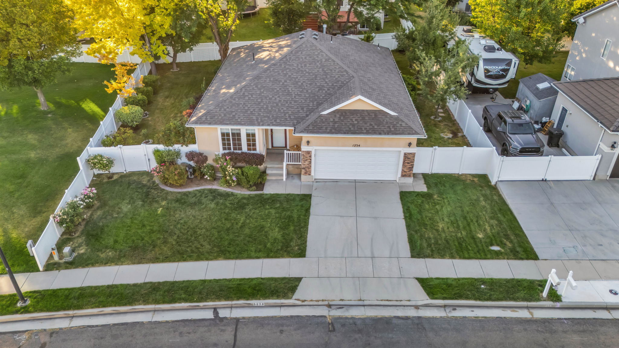 Single-story residence featuring a two-car garage, concrete driveway, and a white vinyl fence