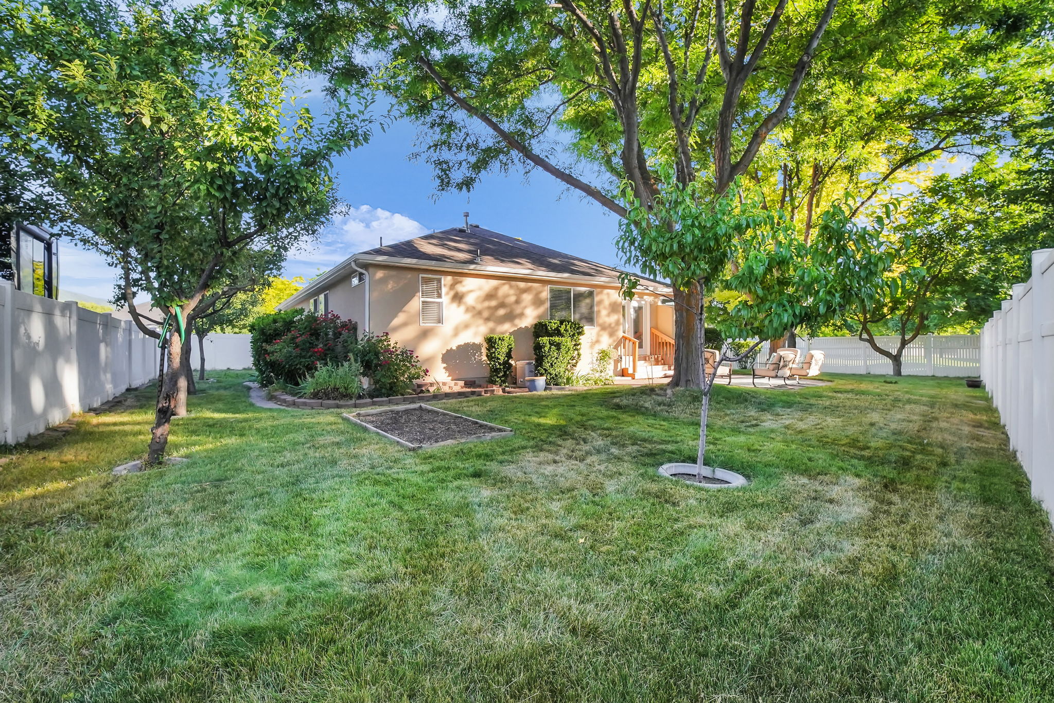 Expansive lawn area featuring mature trees and a vinyl privacy fence