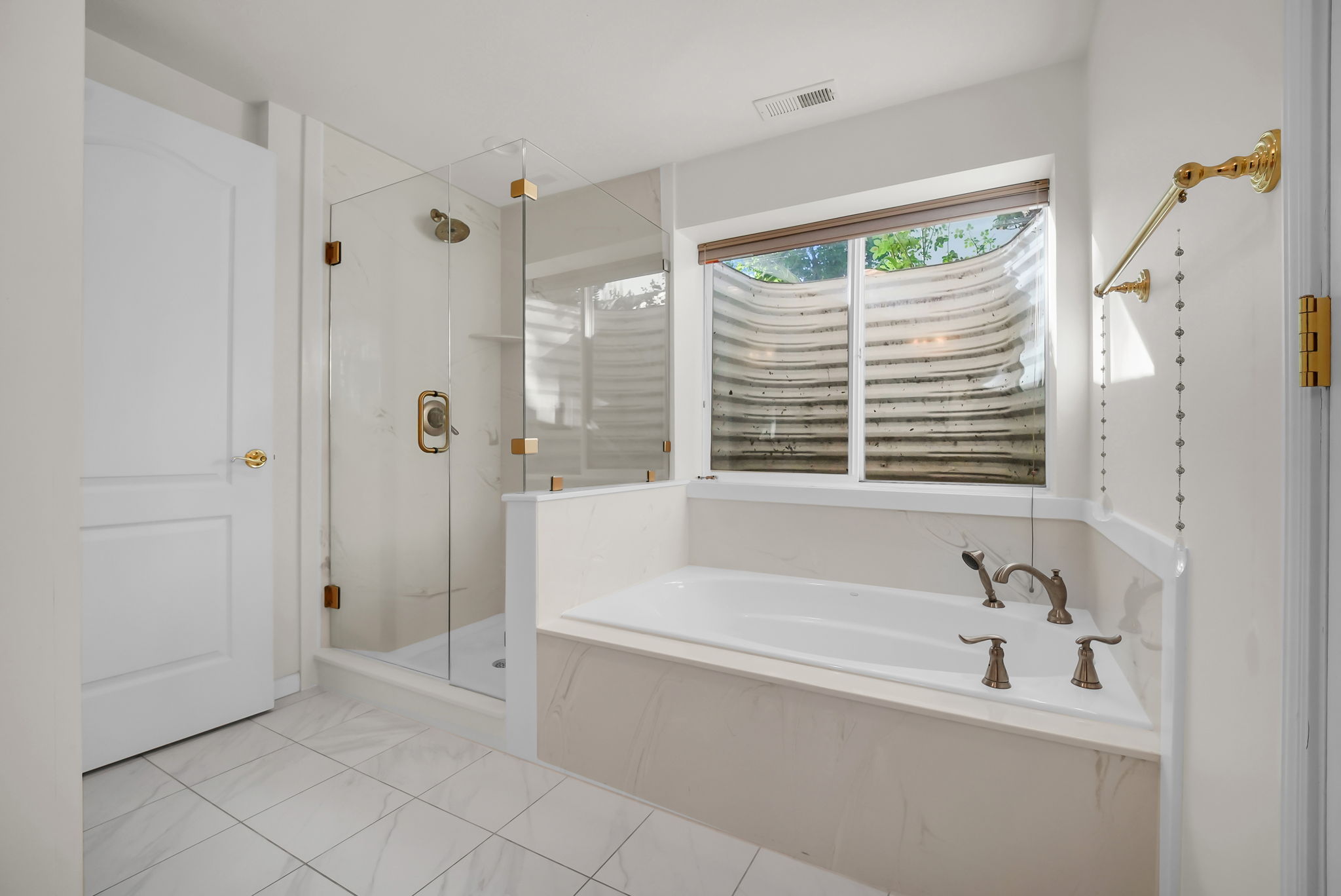 Bathroom featuring a built-in soaking tub with a window, a glass-enclosed shower, white tile flooring, and a white paneled door