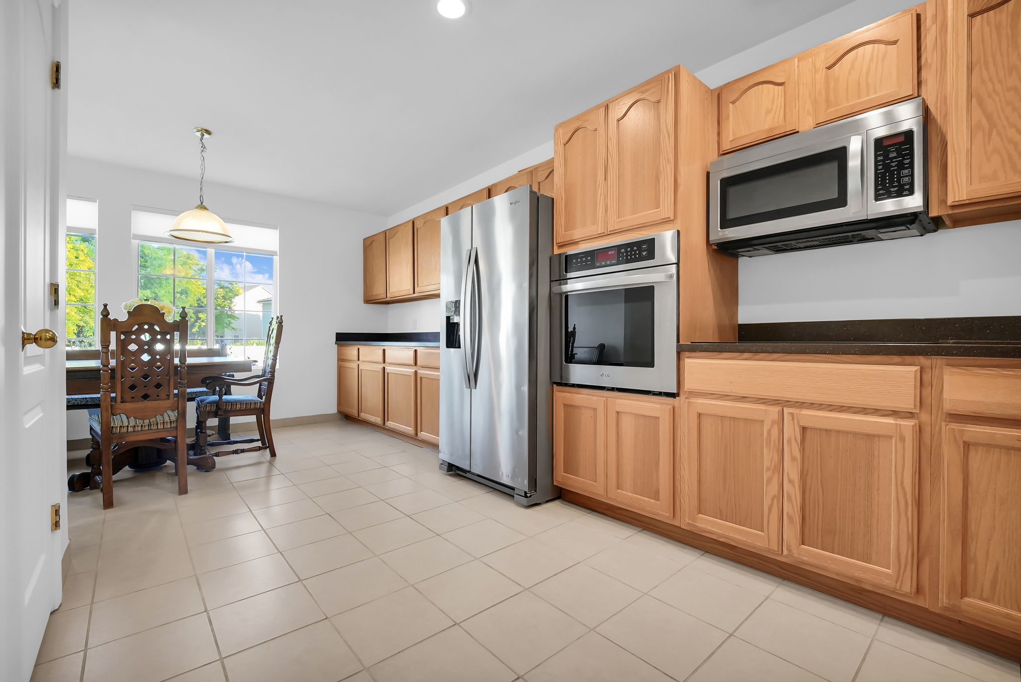 Kitchen featuring wood cabinetry, stainless steel appliances, dark countertops, and tile flooring