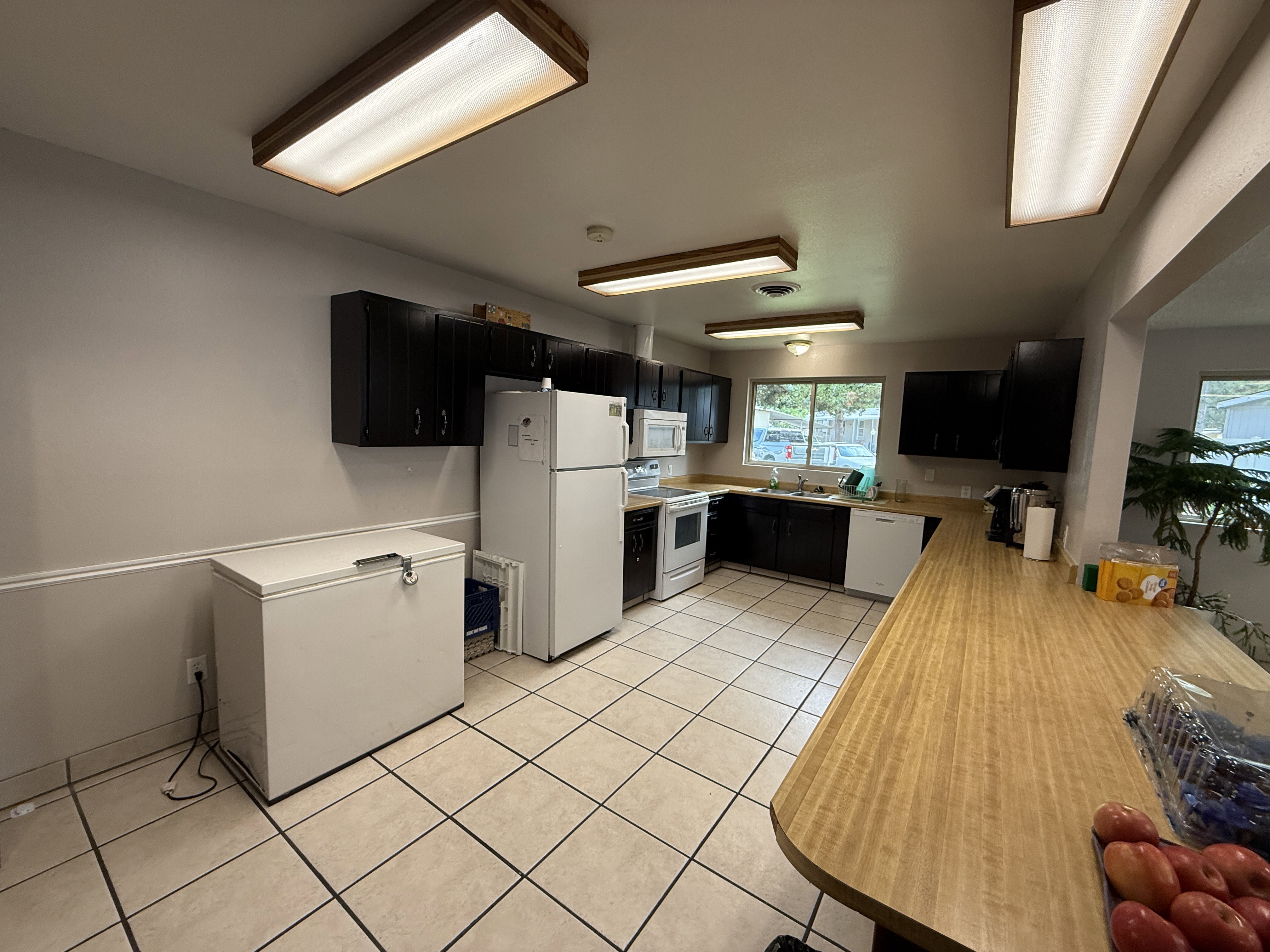 Kitchen featuring black cabinetry, light wood-finish countertops, and tile flooring