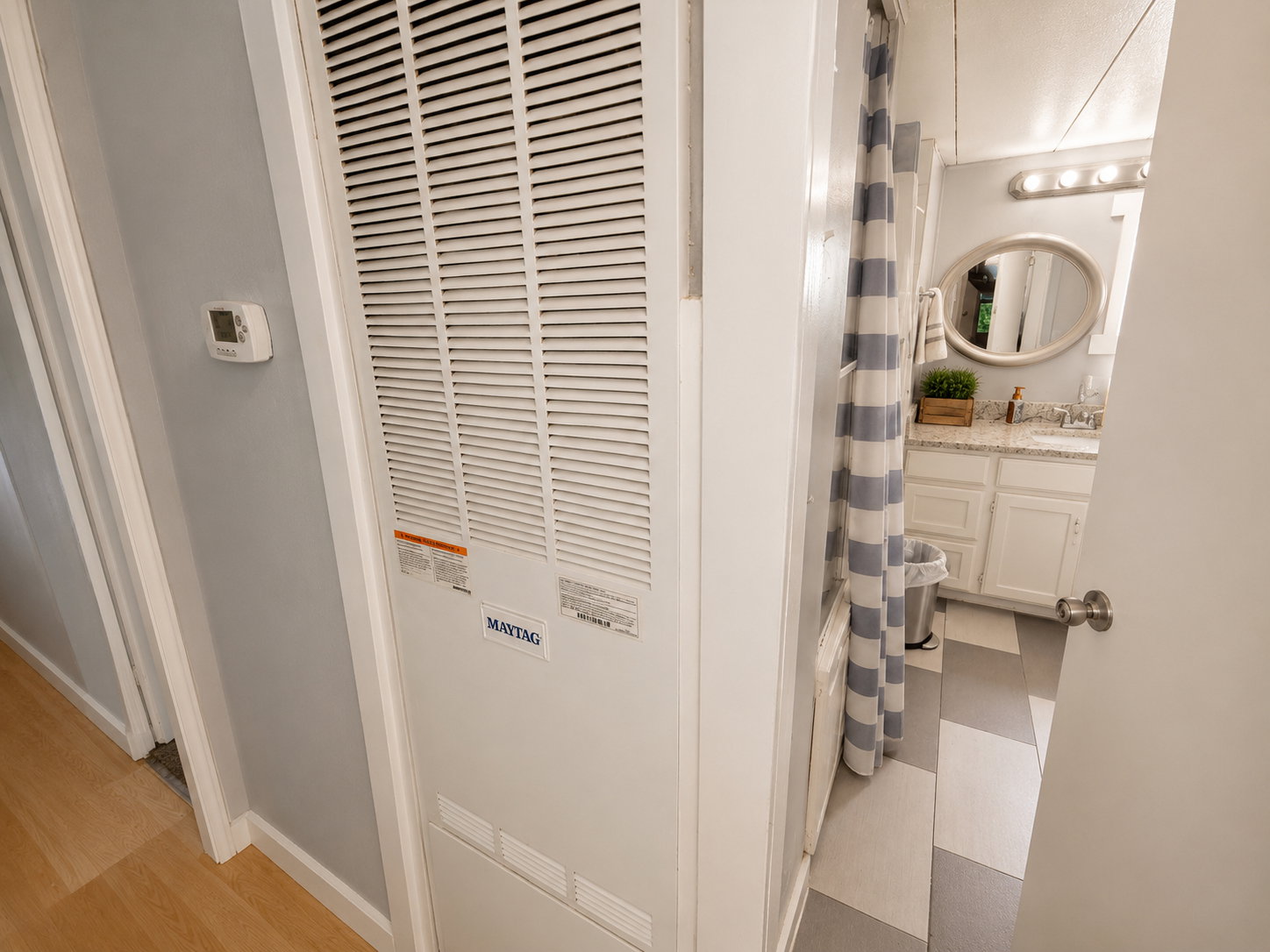 Bathroom featuring a white vanity with a light-colored countertop and an oval mirror, complemented by a patterned shower curtain and geometric floor tiles
