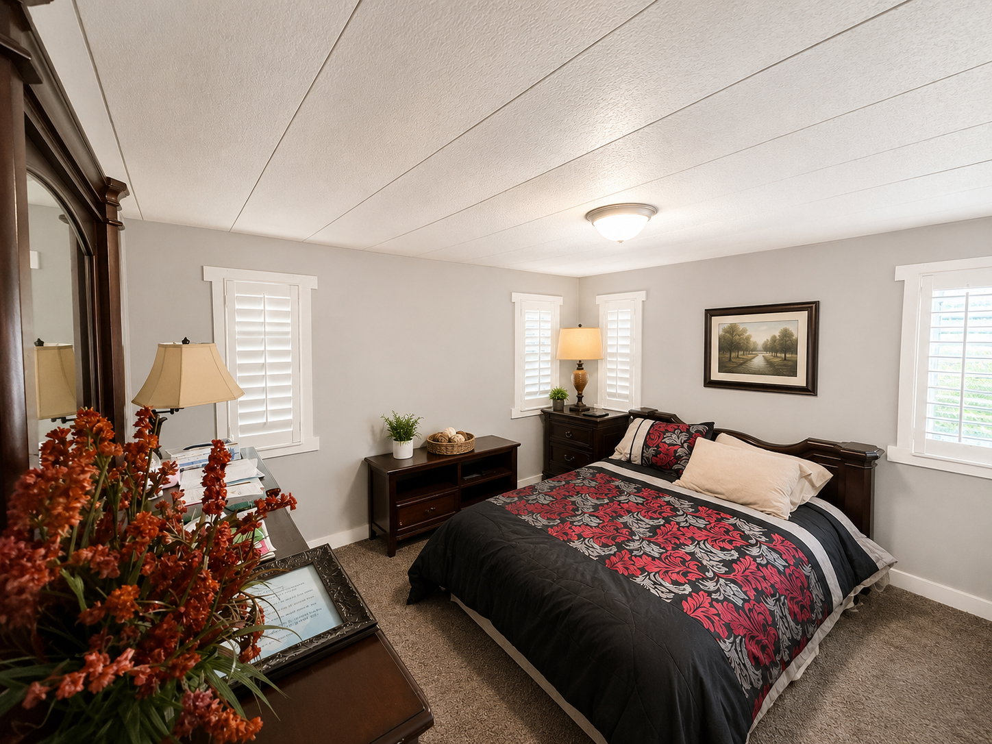 Carpeted bedroom featuring light gray walls, white trim, and two windows with white plantation shutters
