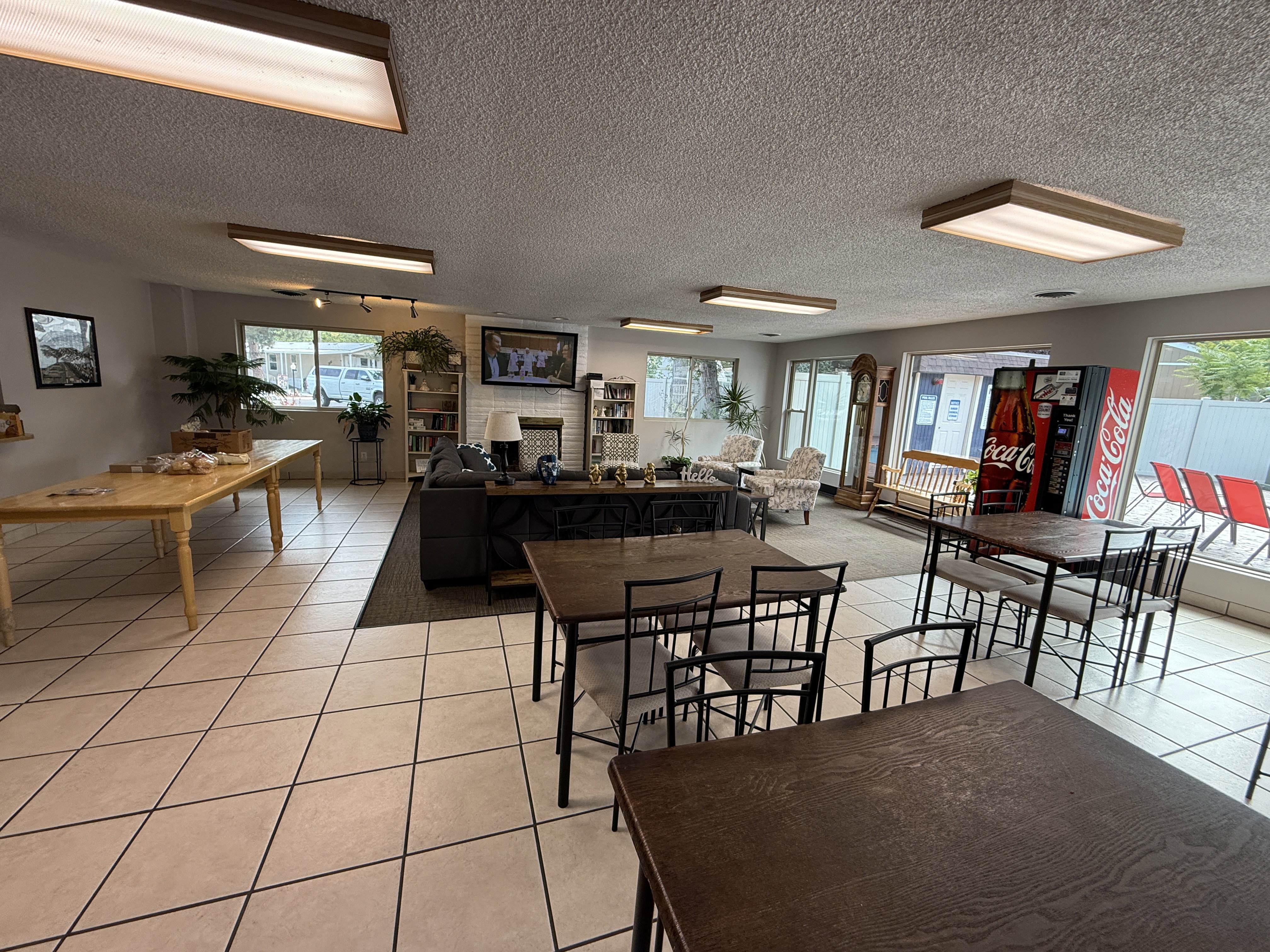 Spacious common area featuring large windows, a tiled floor, and a distinct carpeted seating zone