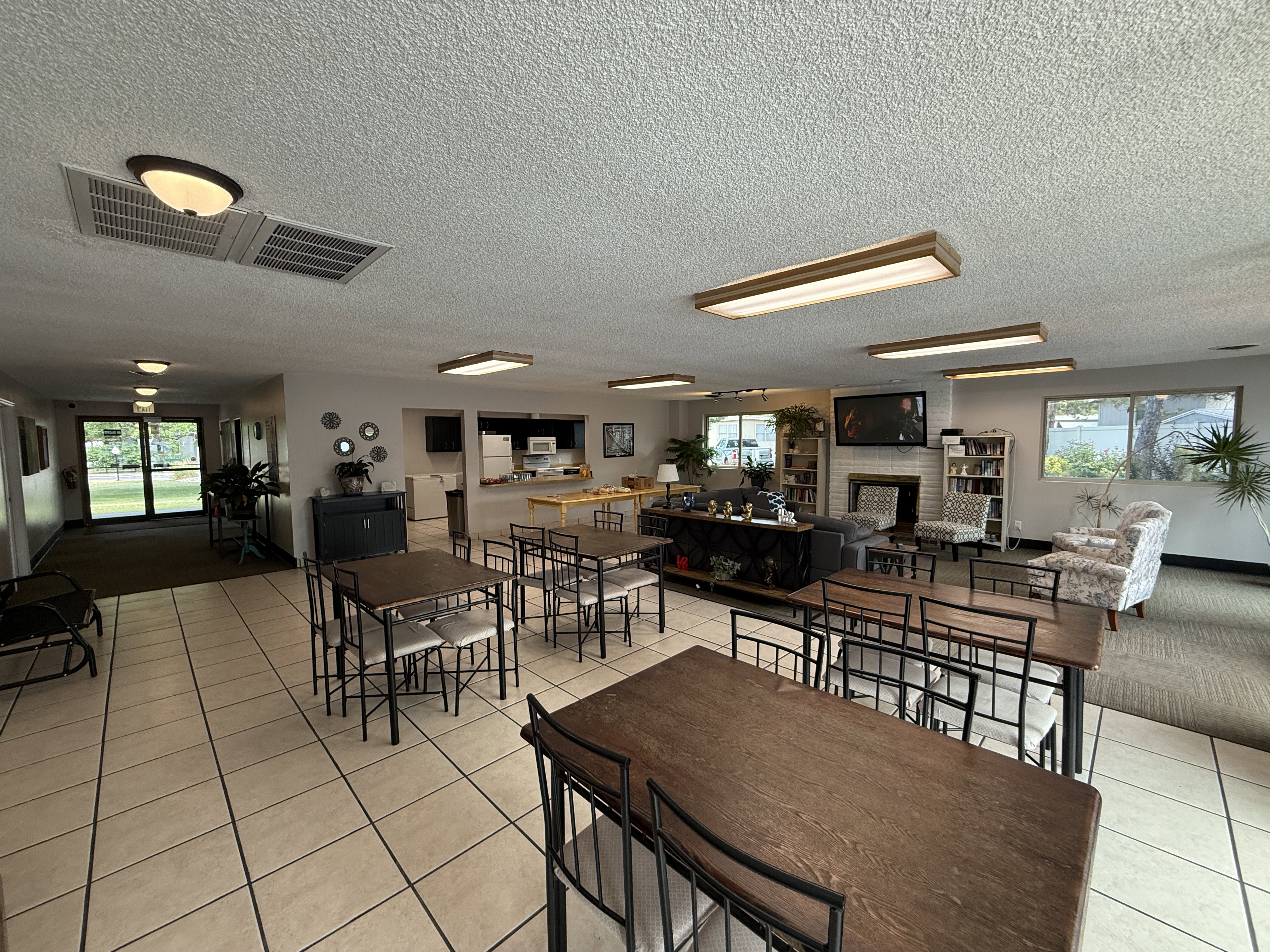 Open-concept common area featuring tile flooring, a fireplace with a white brick surround, built-in shelving, and large windows