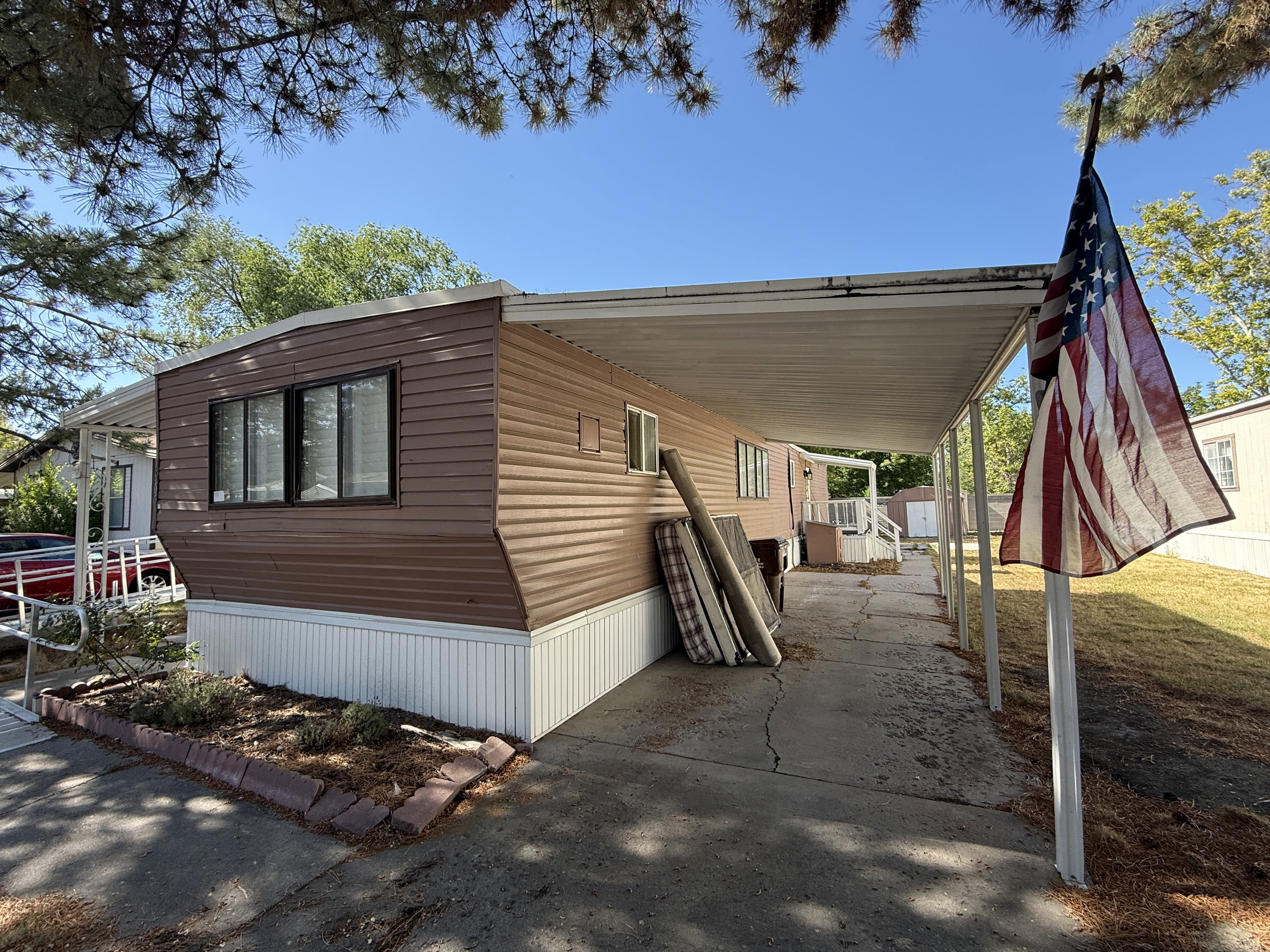 Brown horizontal siding with white trim and a covered carport
