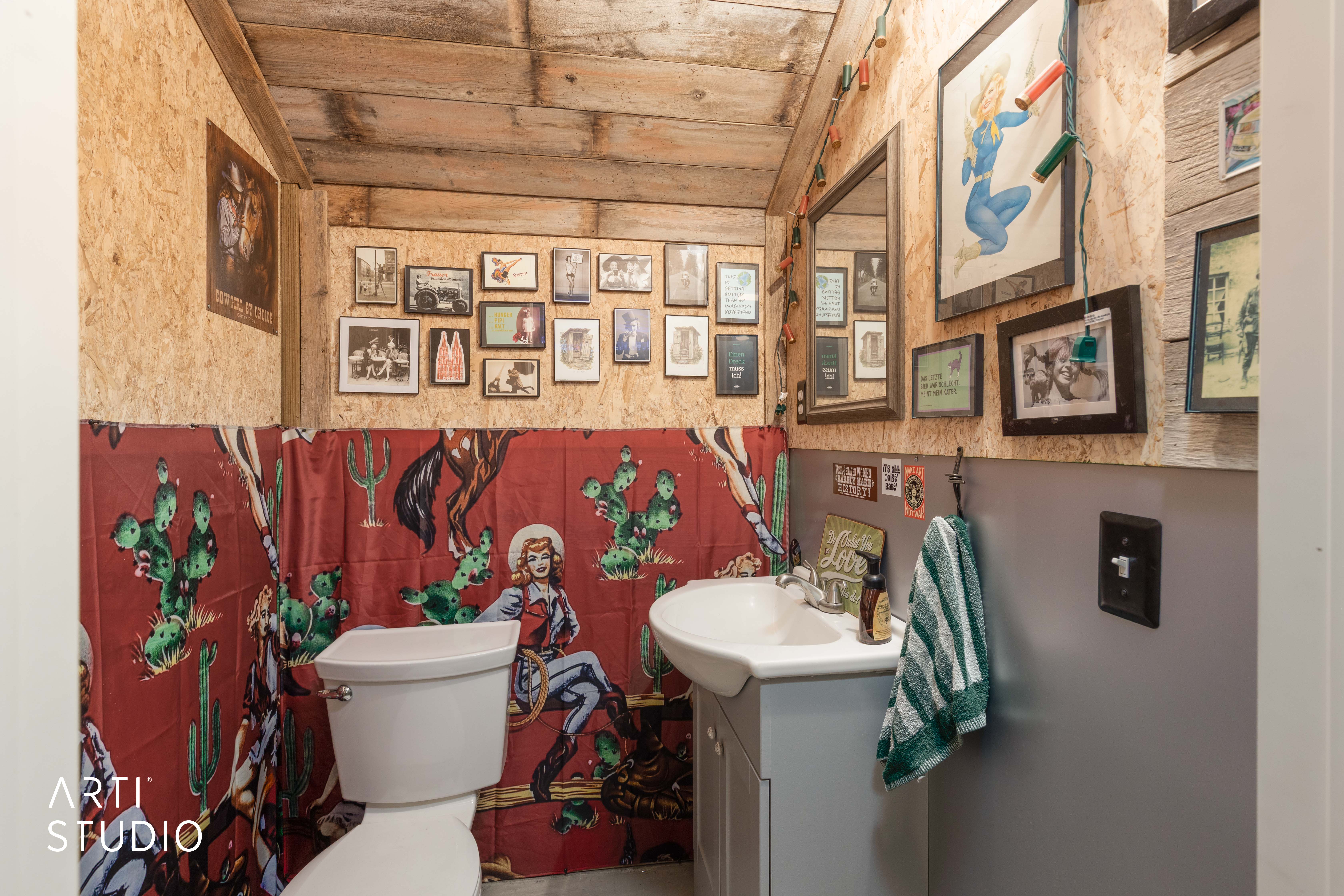 Restroom featuring wood-finish walls and ceiling, a white toilet, and a white pedestal sink with a light grey vanity