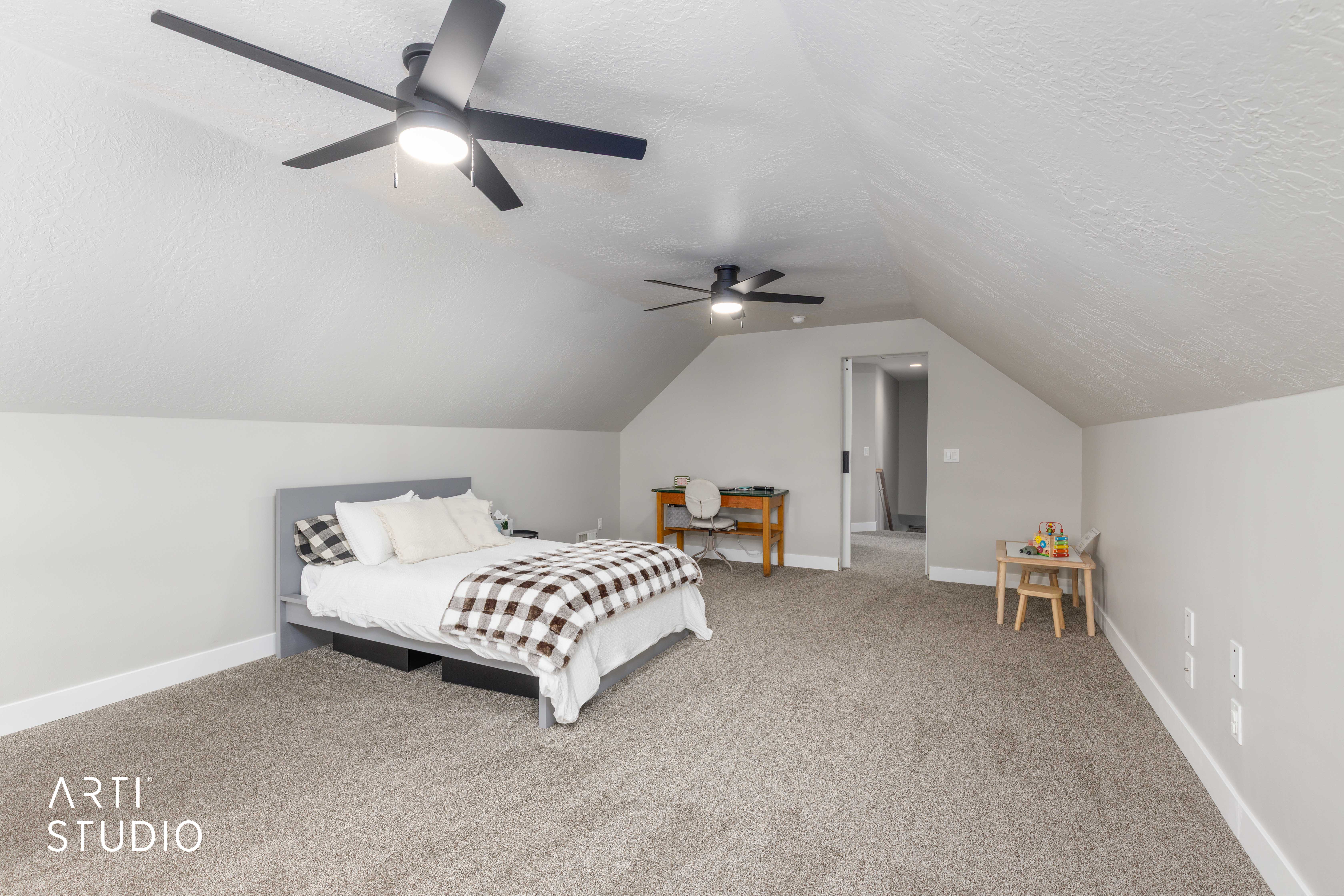 Spacious room featuring vaulted ceilings, plush carpeting, contemporary ceiling fans with integrated lighting, and neutral wall tones