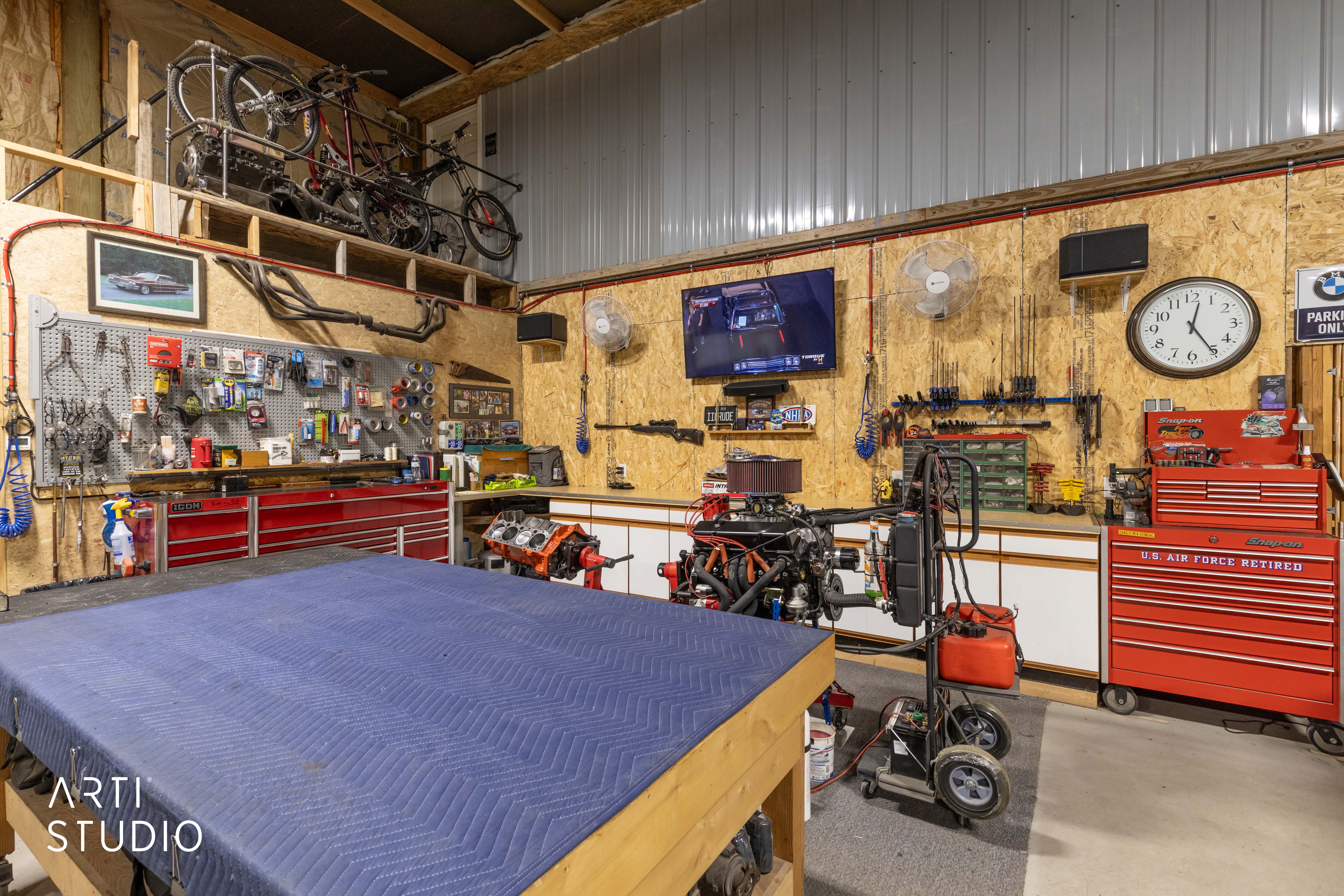 Dedicated workshop space featuring ample built-in storage, a large work surface, and overhead shelving