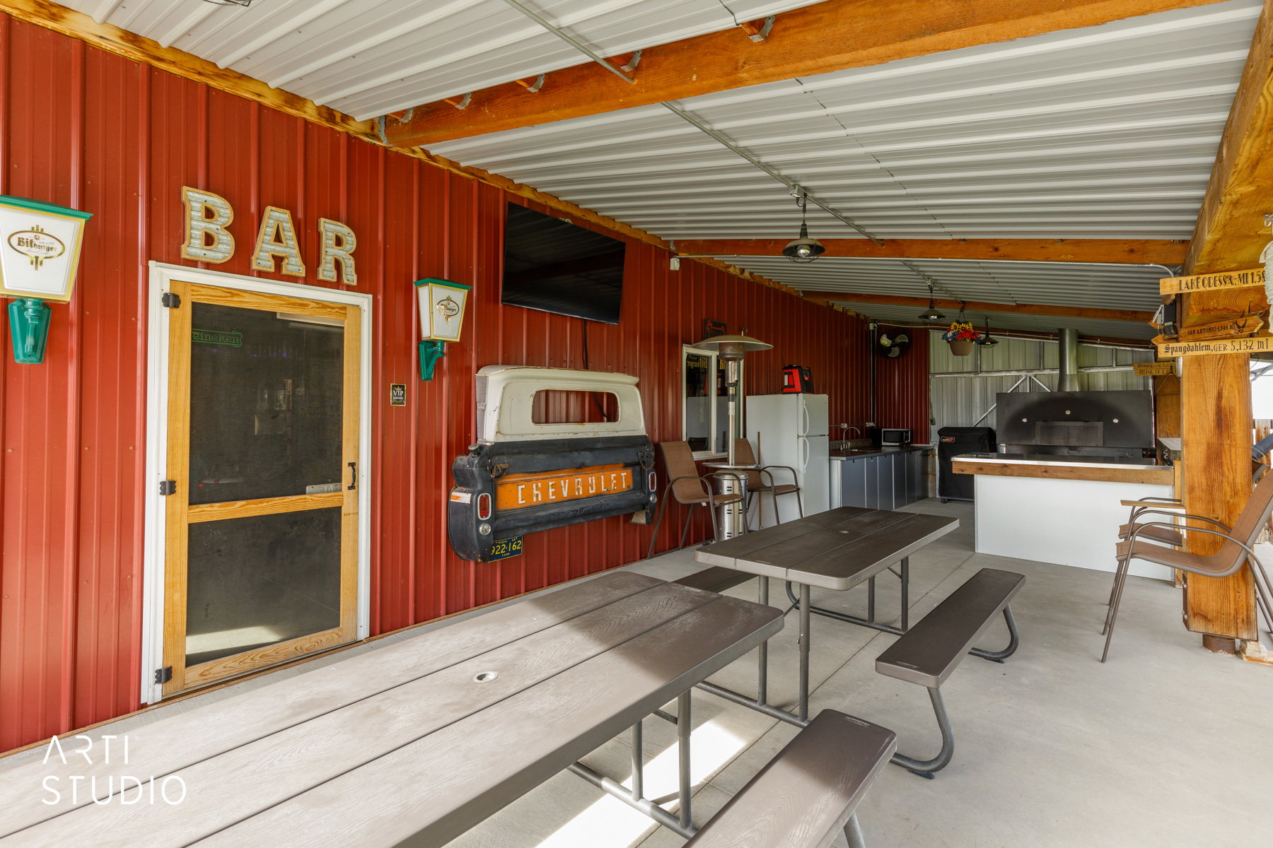 Covered outdoor entertainment area featuring a red corrugated metal wall and a metal ceiling