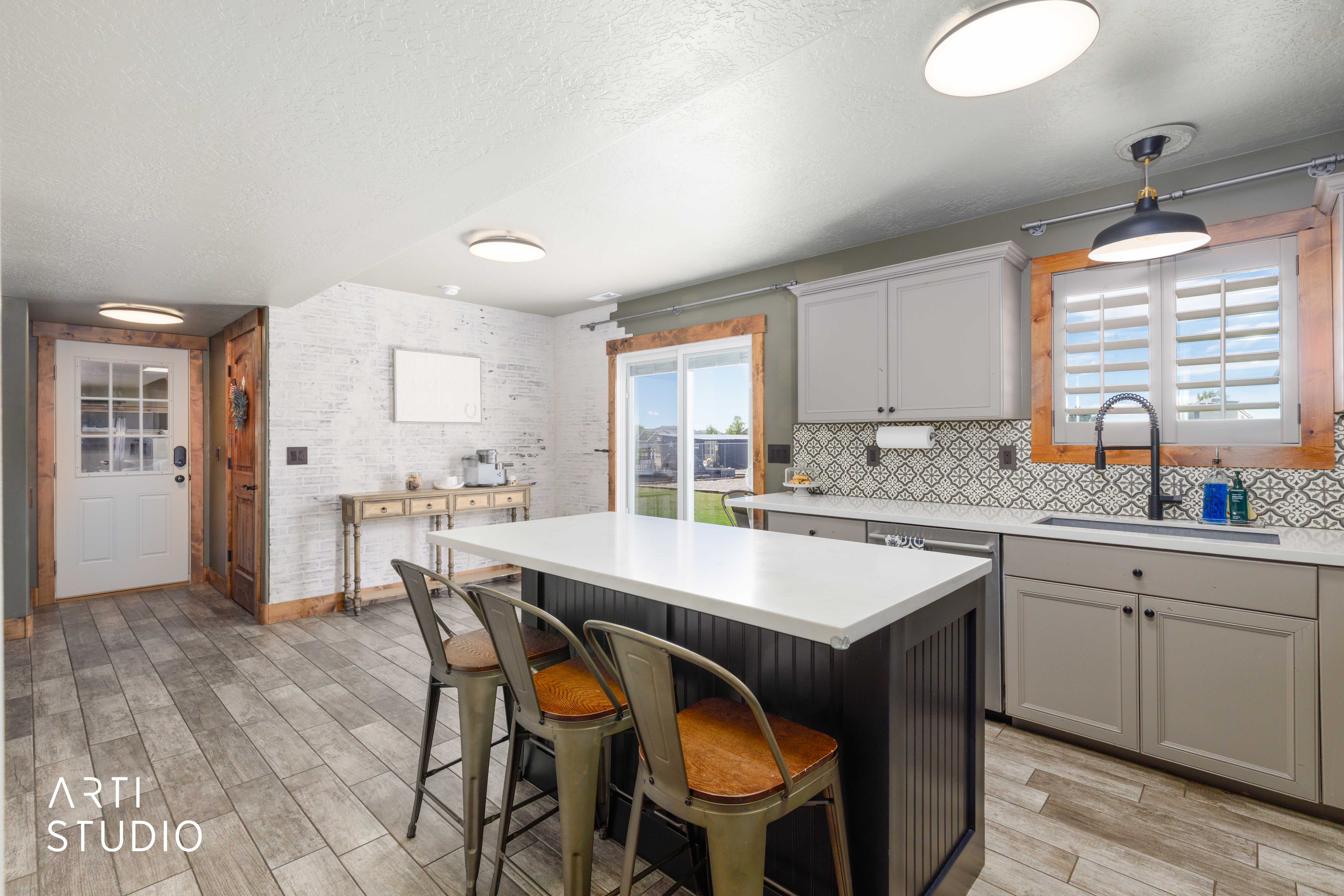 Modern kitchen featuring tile flooring, a central island with a white countertop, light gray cabinetry, and a patterned tile backsplash