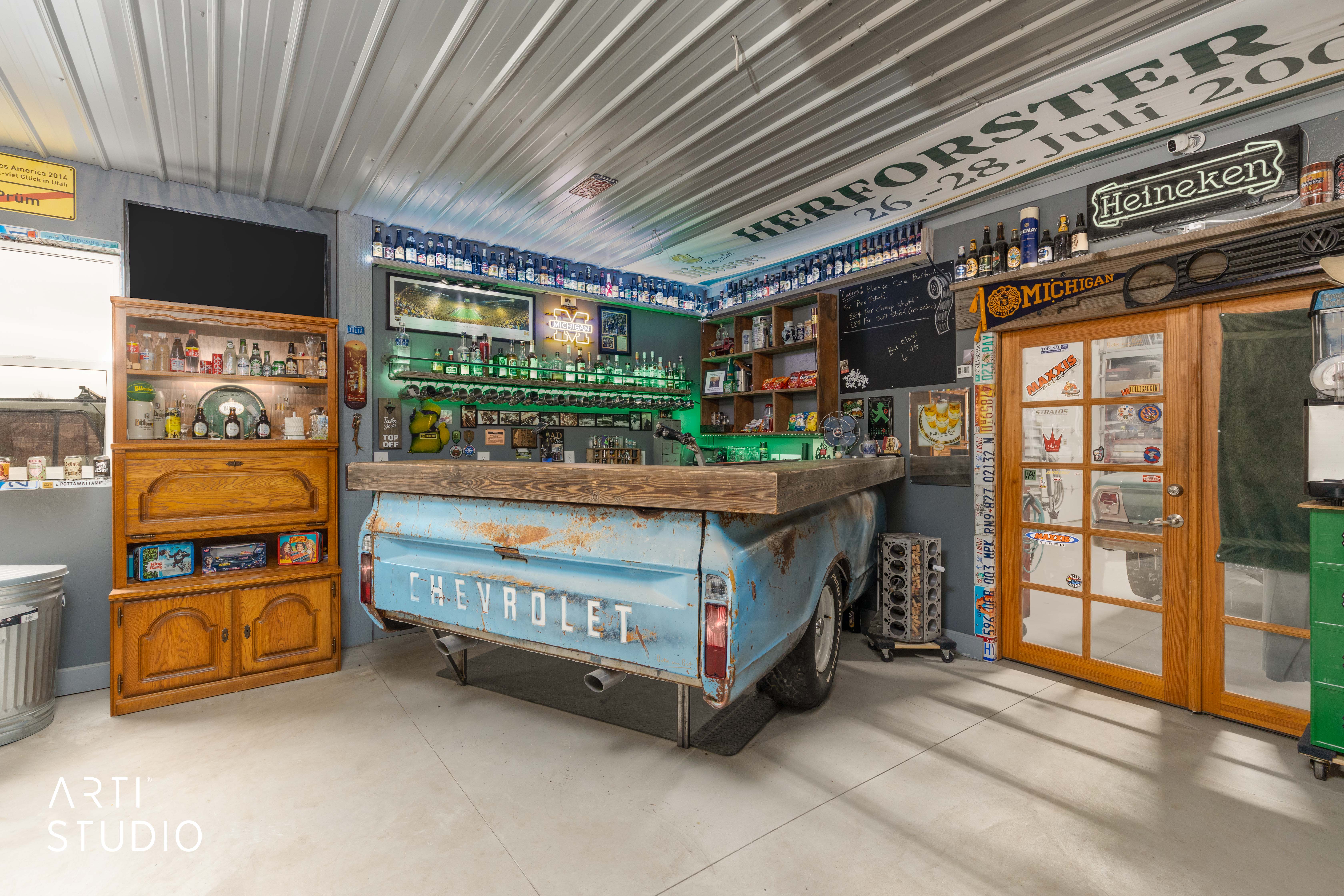 Custom bar area featuring a unique automotive-themed counter, integrated shelving, and illuminated display alcoves