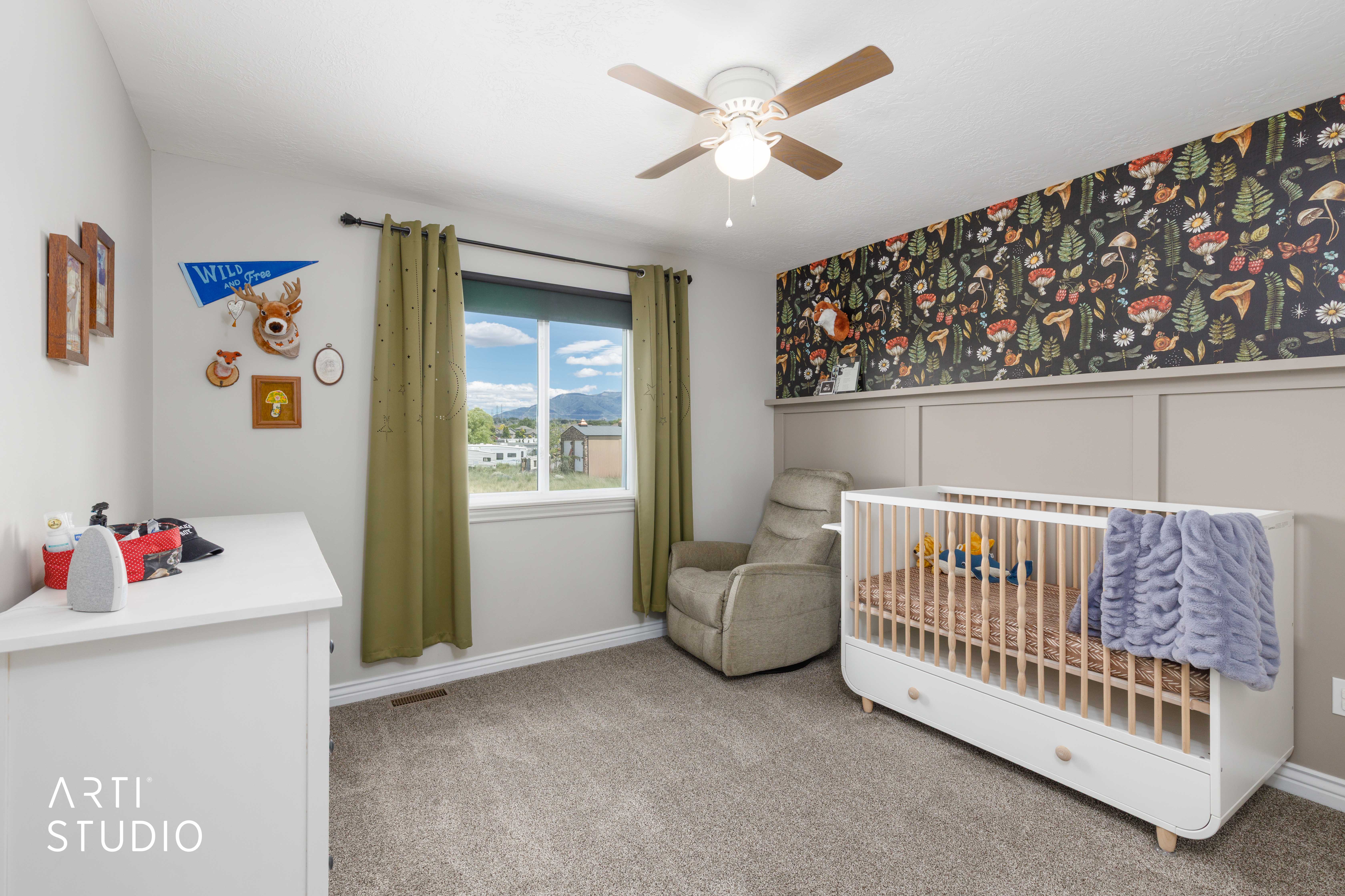 Carpeted bedroom featuring a wood-finish ceiling fan, a window with mountain and sky scenery, and a decorative accent wall with paneling
