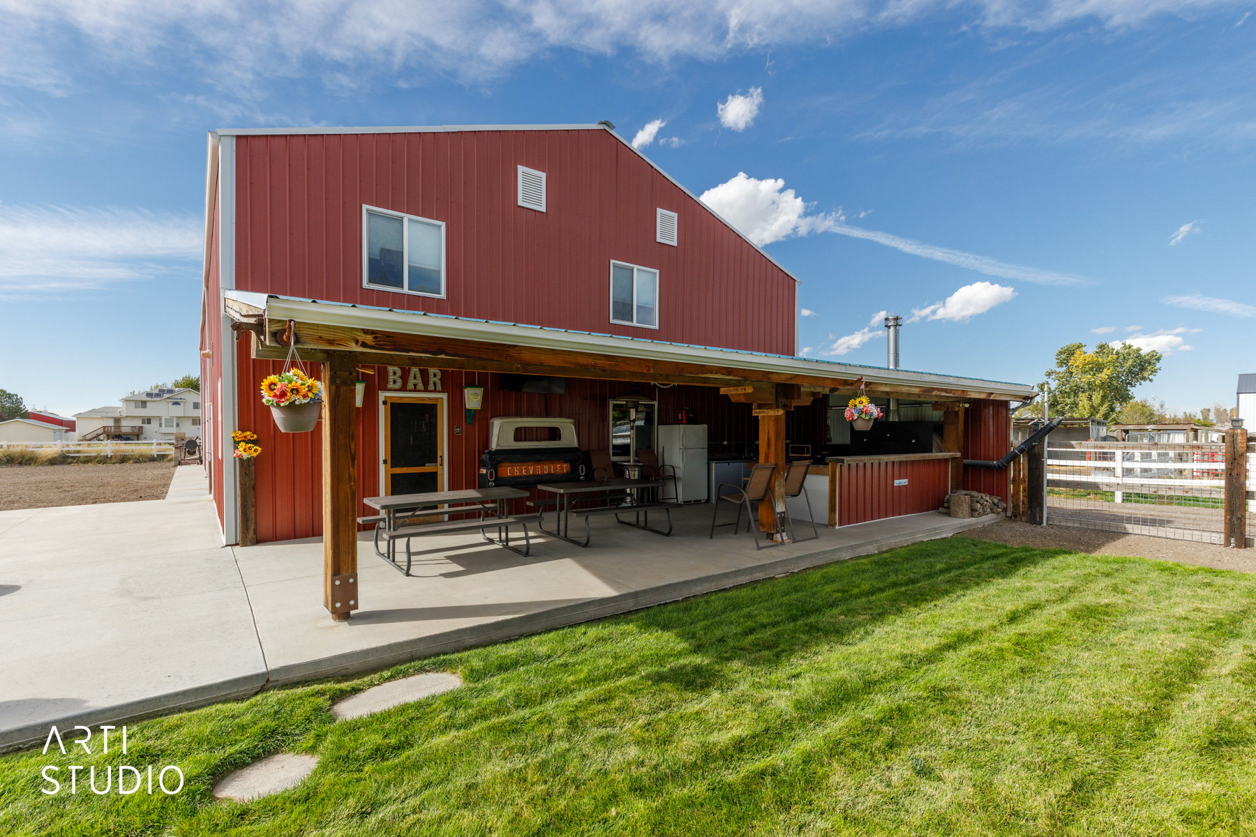 Red metal-sided structure featuring a covered patio with an outdoor kitchen area