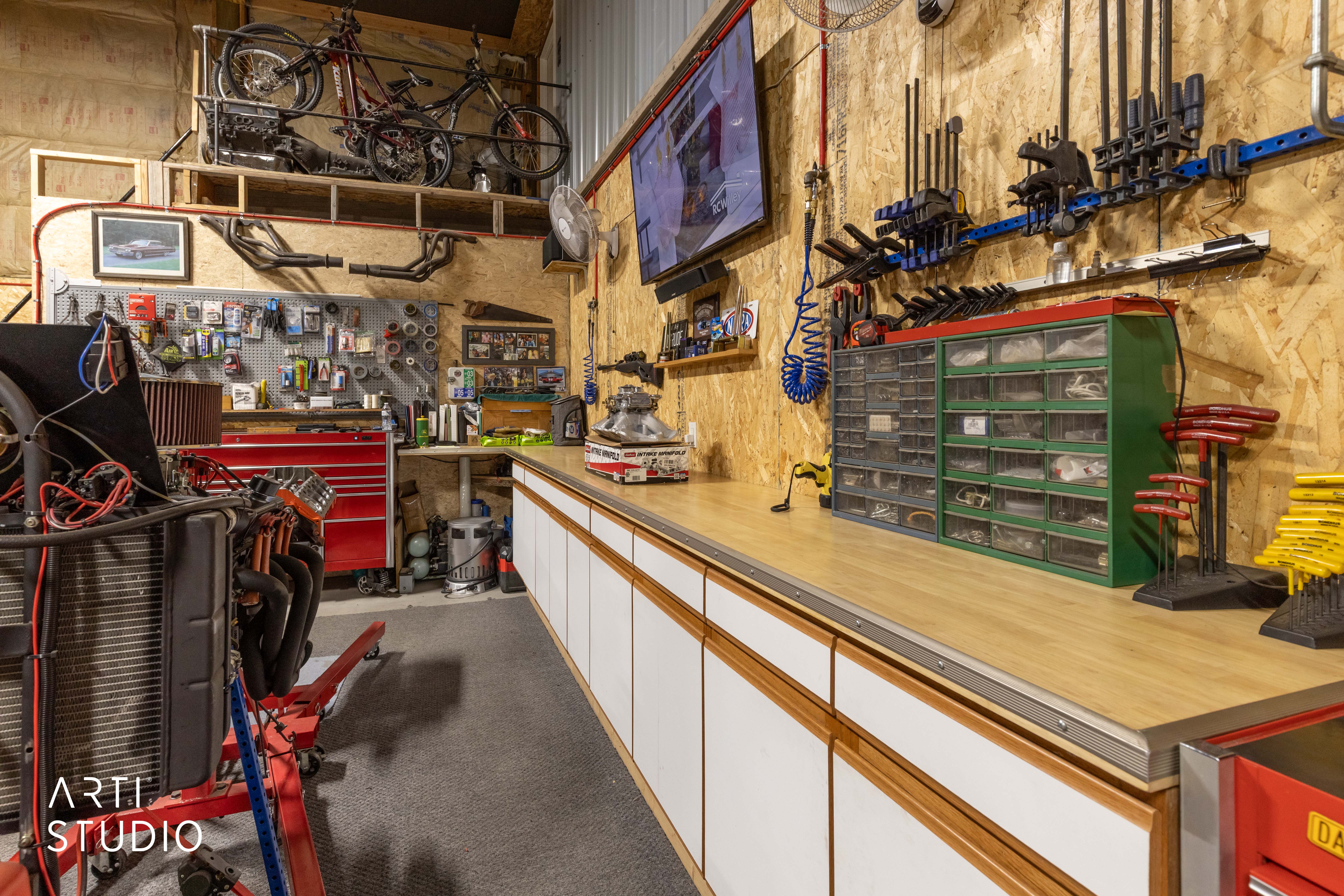 Spacious workshop featuring wood-finish walls, a long built-in workbench with white cabinetry