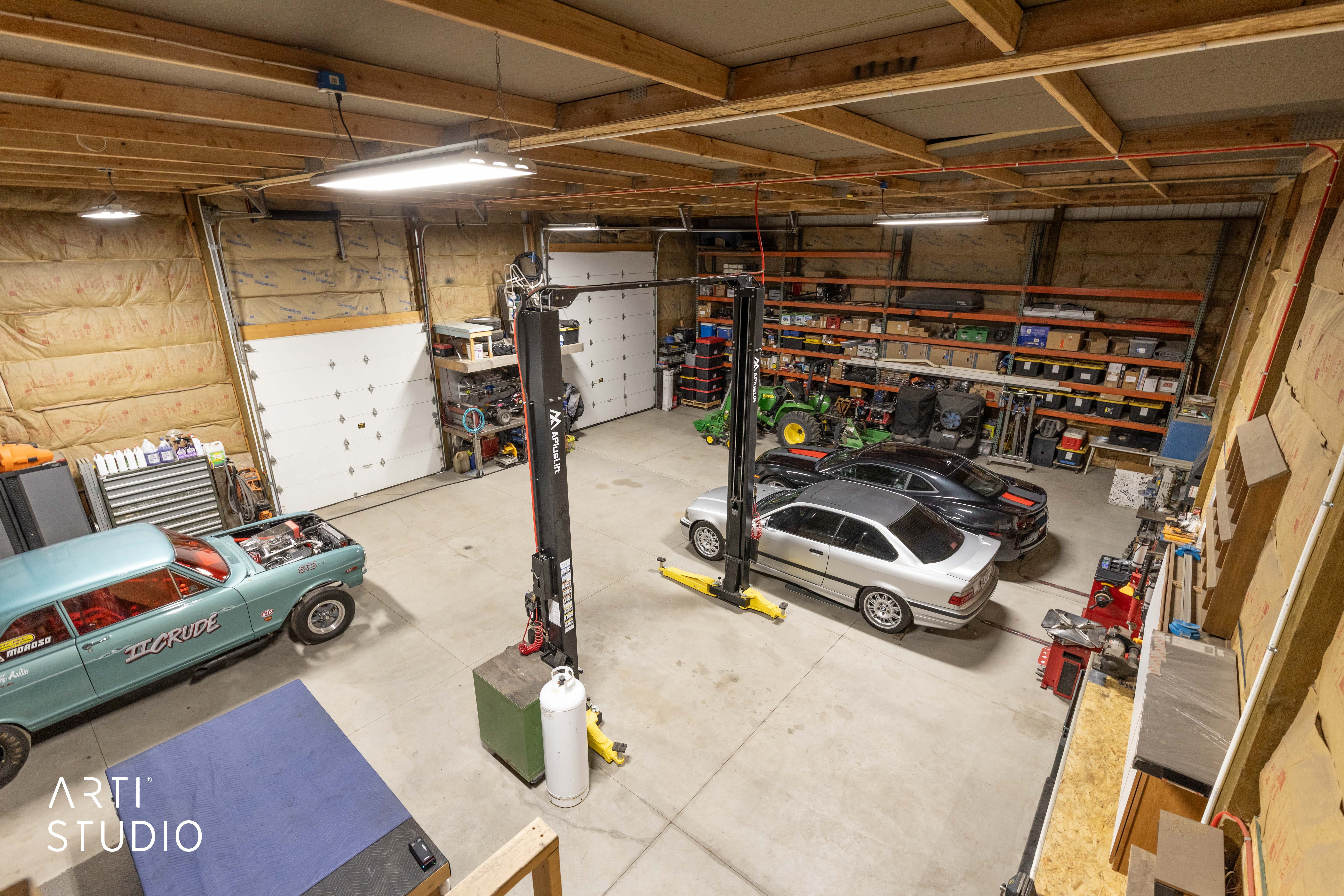 Spacious garage featuring exposed ceiling beams, concrete flooring, and multiple overhead fluorescent light fixtures