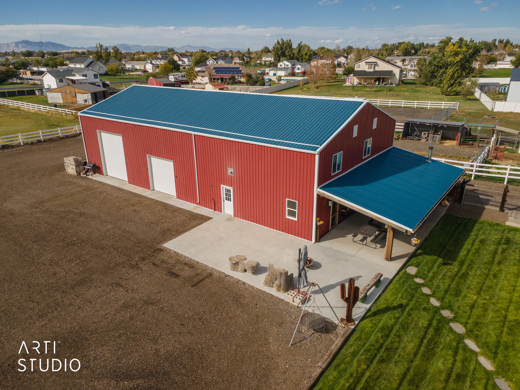 Red metal building with a blue metal roof and an attached covered patio