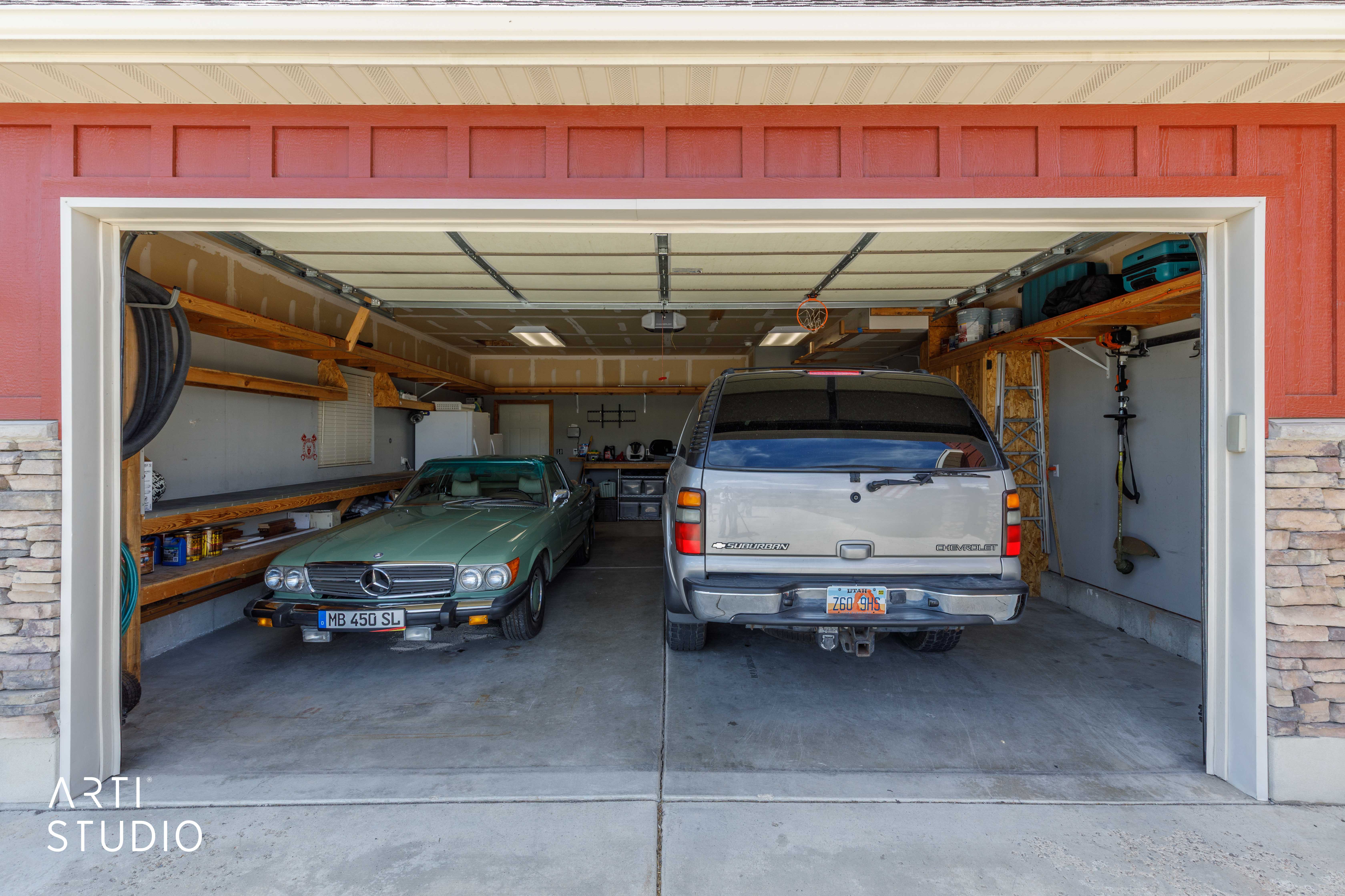 Two-car garage featuring concrete flooring, built-in shelving, overhead lighting, and a paneled garage door
