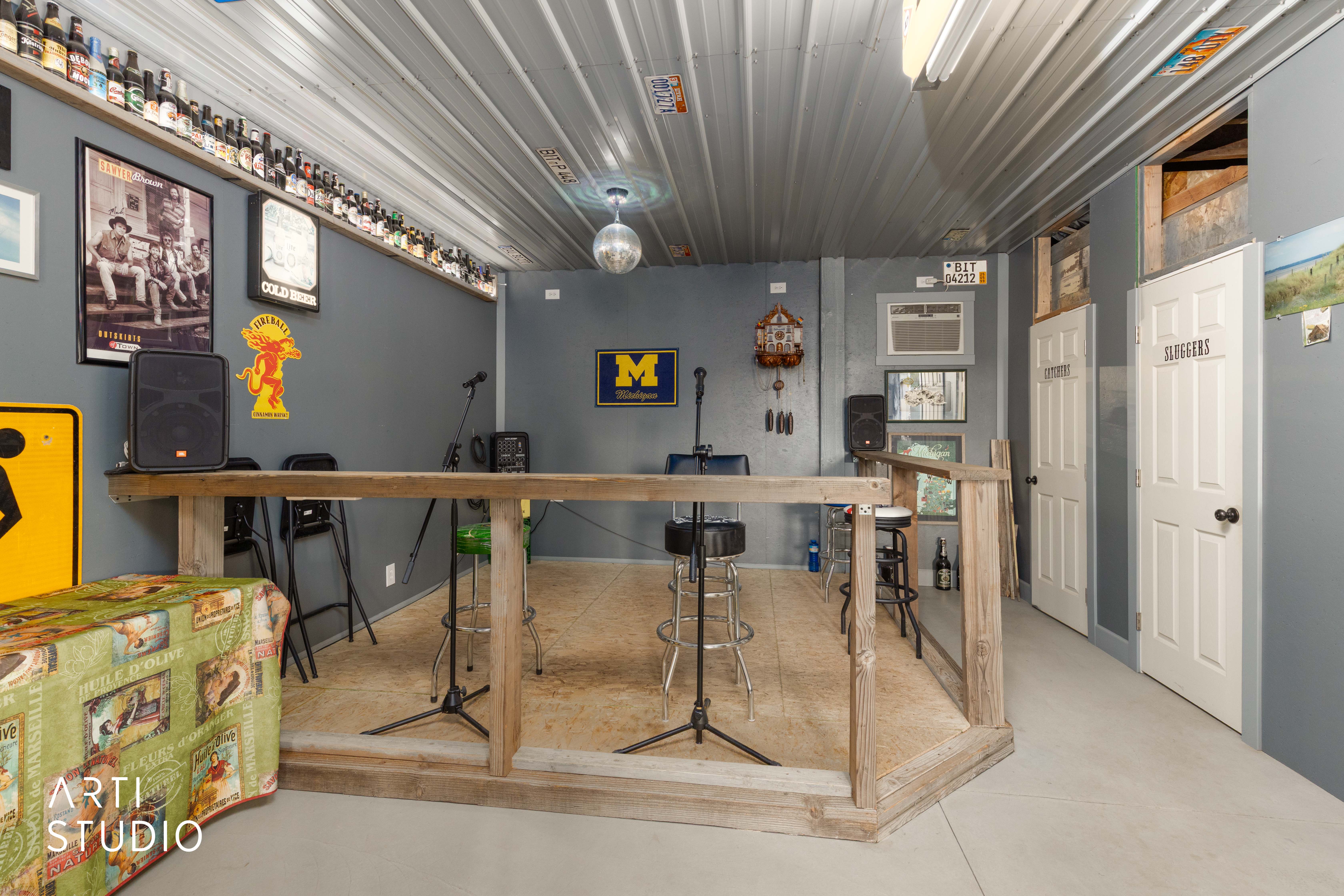 Interior space featuring a raised wood-framed stage, corrugated metal ceiling, and two white panel doors