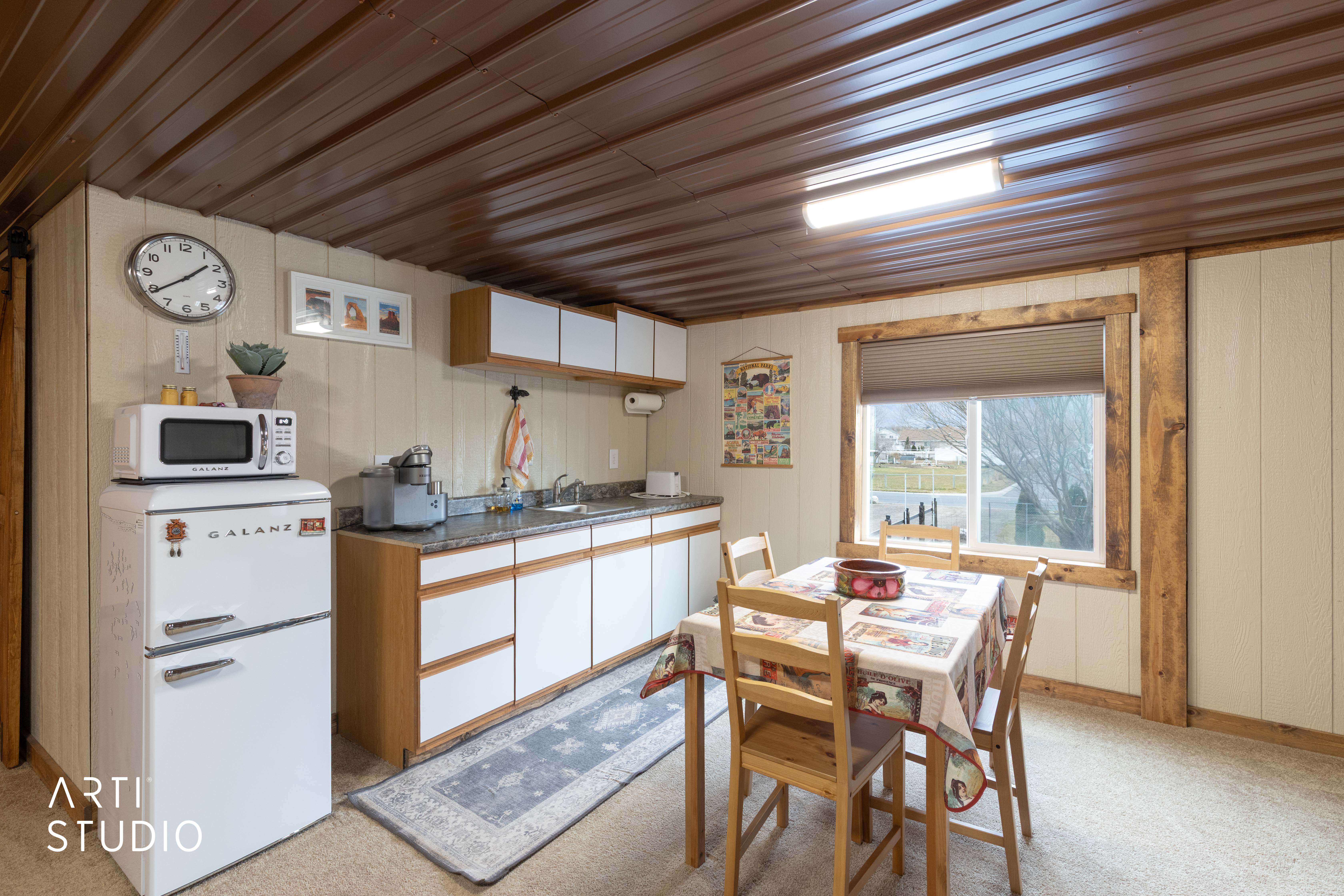 Compact kitchen area featuring wood-finish cabinetry, granite-style countertops, white paneling, and a wood-paneled ceiling
