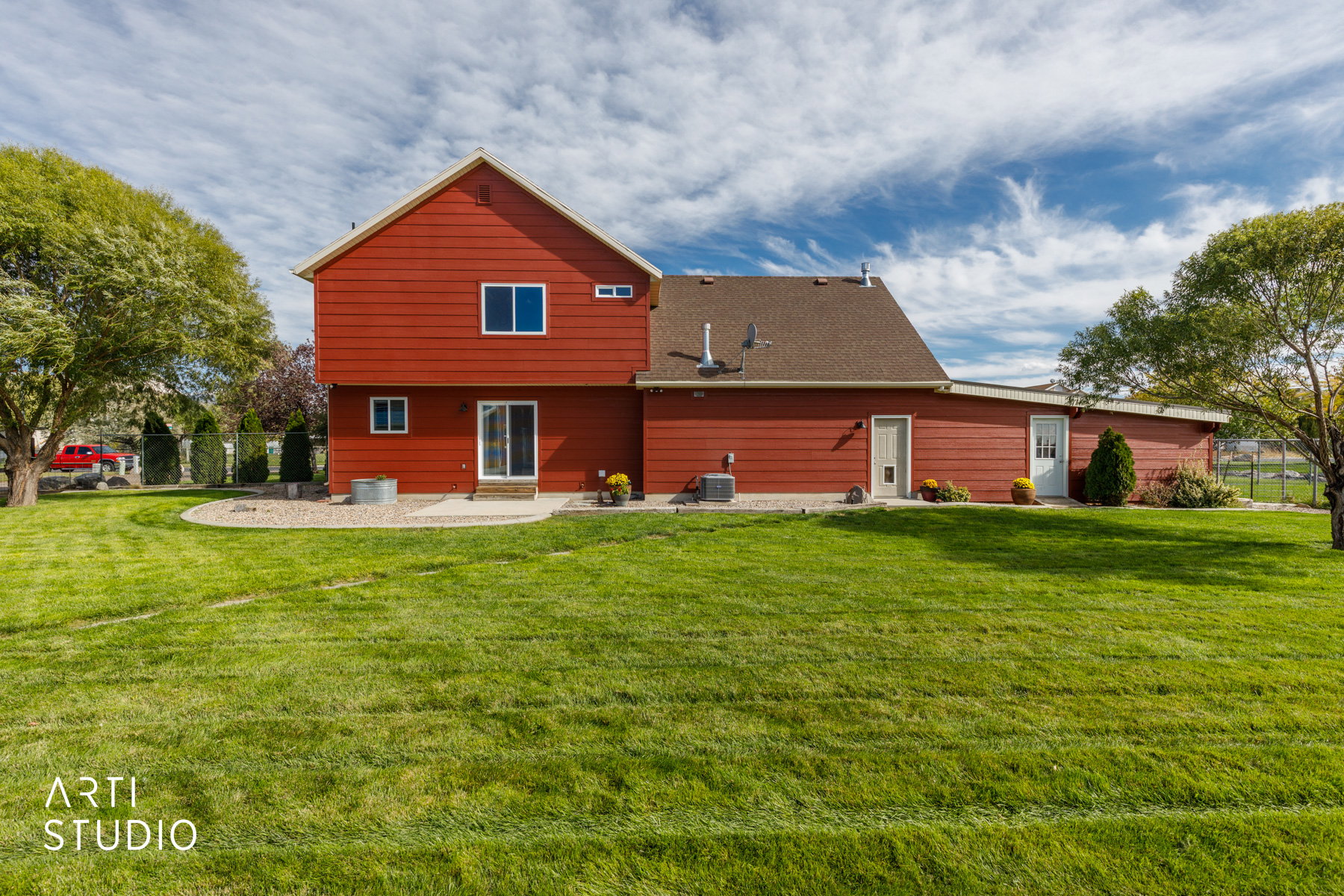 Red siding exterior with a brown shingle roof, featuring a sliding glass door and multiple windows