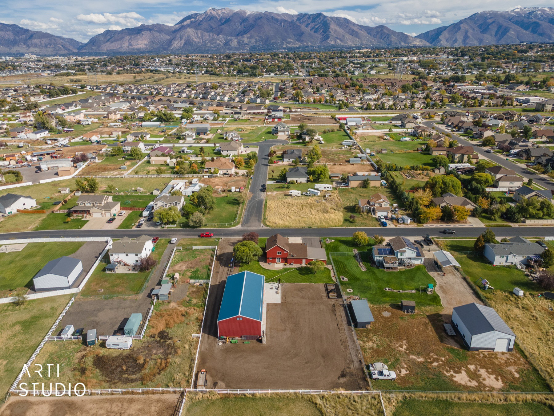Aerial perspective showcasing a property with a red barn structure featuring a blue roof