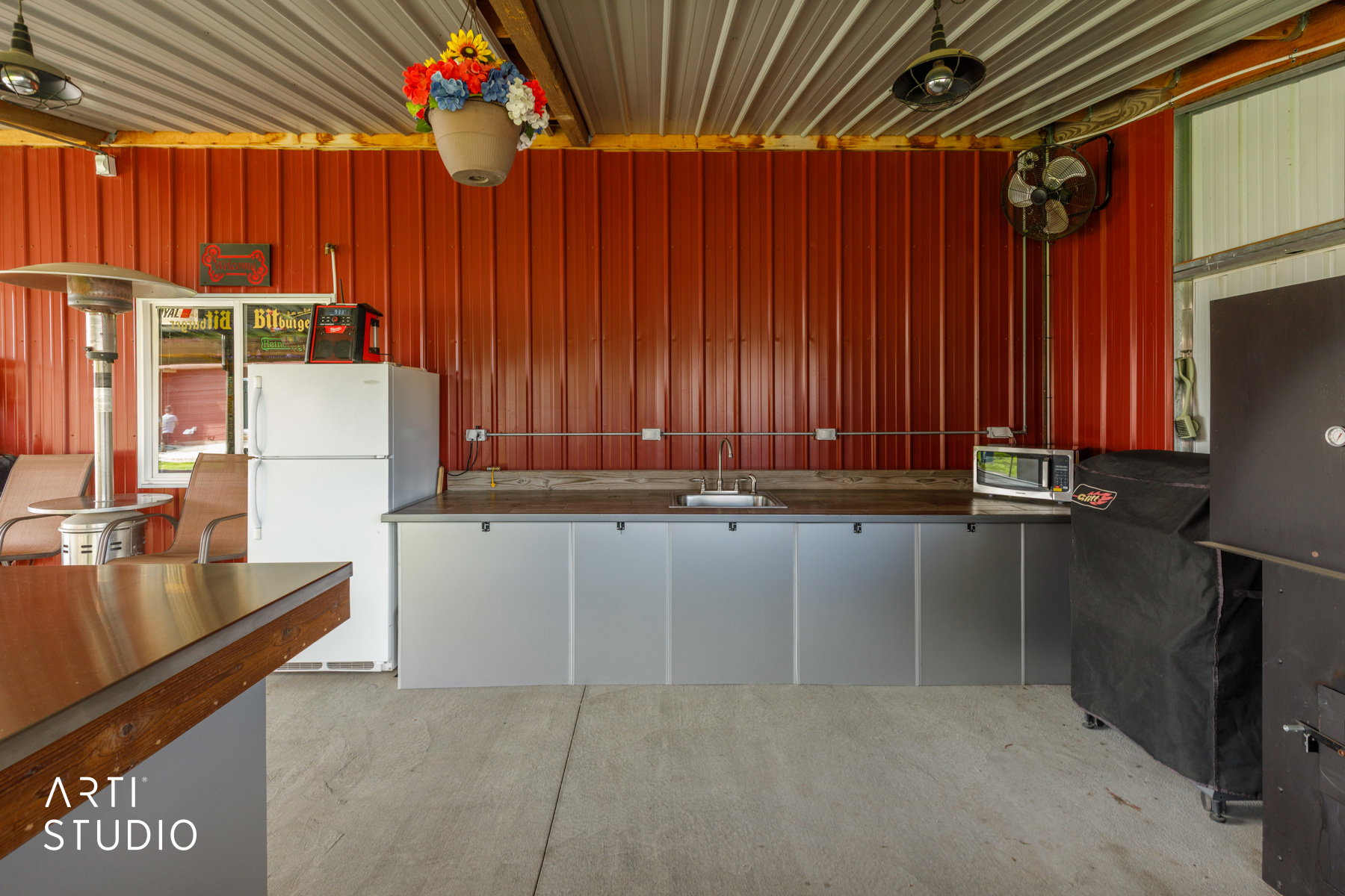 Outdoor kitchen area featuring a corrugated metal ceiling and red panel wall