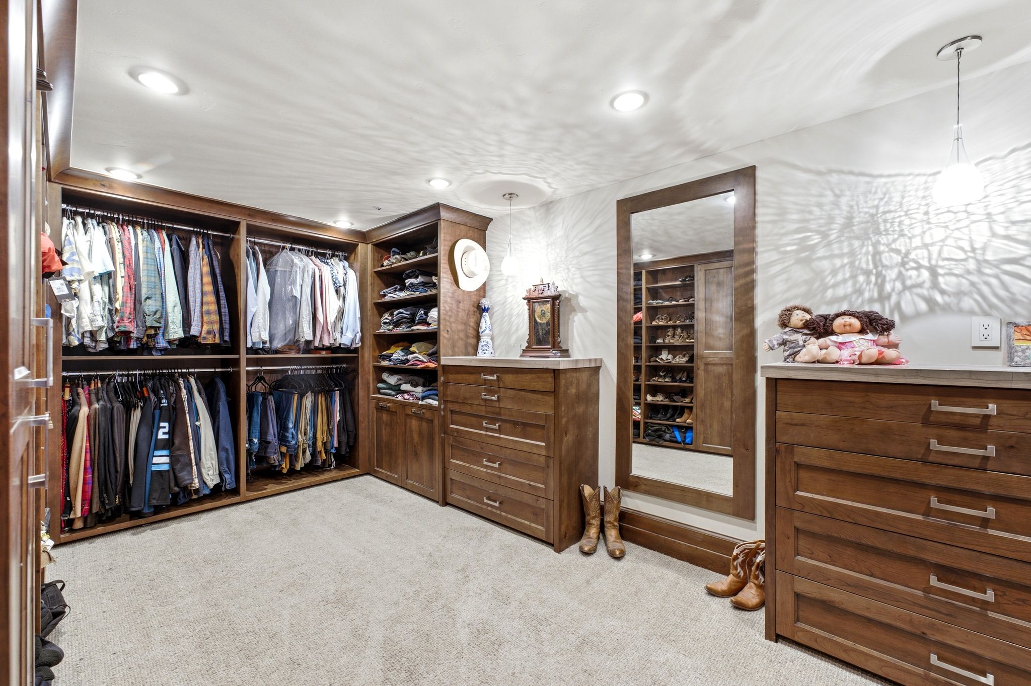 Spacious walk-in closet featuring extensive custom wood cabinetry, built-in shelving, multiple hanging rods, and integrated drawer storage